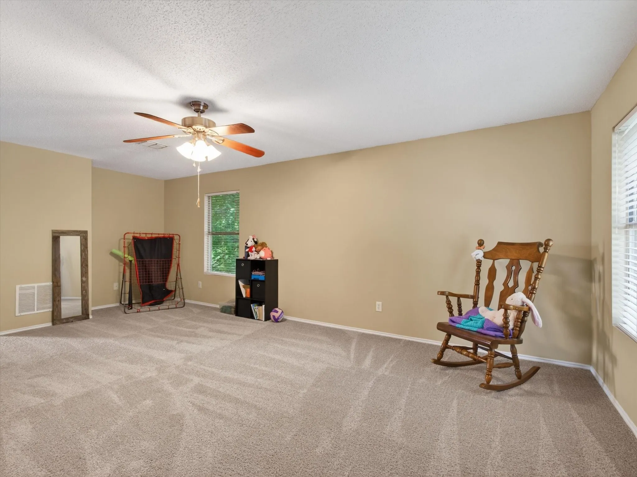 Expansive room featuring plush wall-to-wall carpeting, neutral wall tones, and white baseboards
