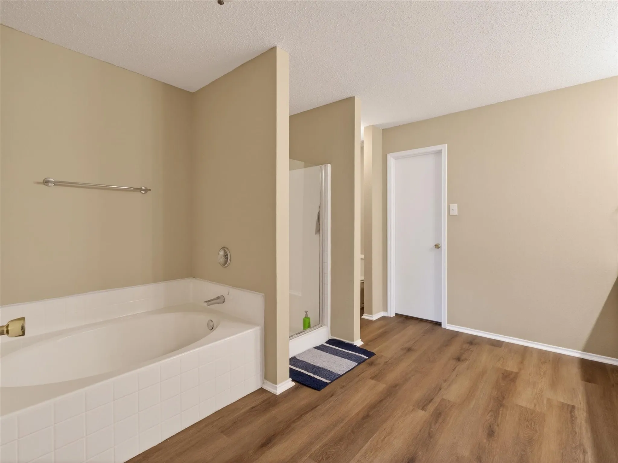 Soaking tub with white tile surround, adjacent to a glass-enclosed shower
