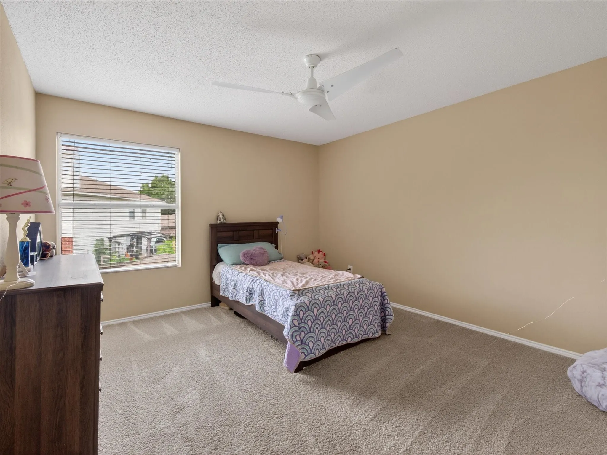 Carpeted room featuring a ceiling fan, window with horizontal blinds, and neutral wall tones
