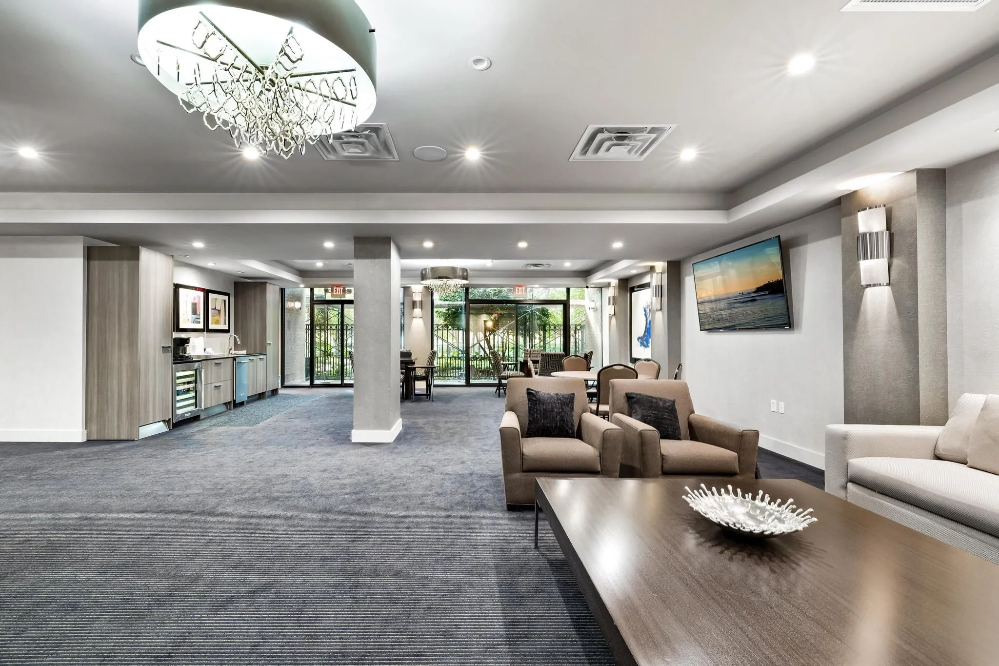 Spacious common area featuring recessed lighting, a modern chandelier, and a built-in refreshment bar with a beverage cooler