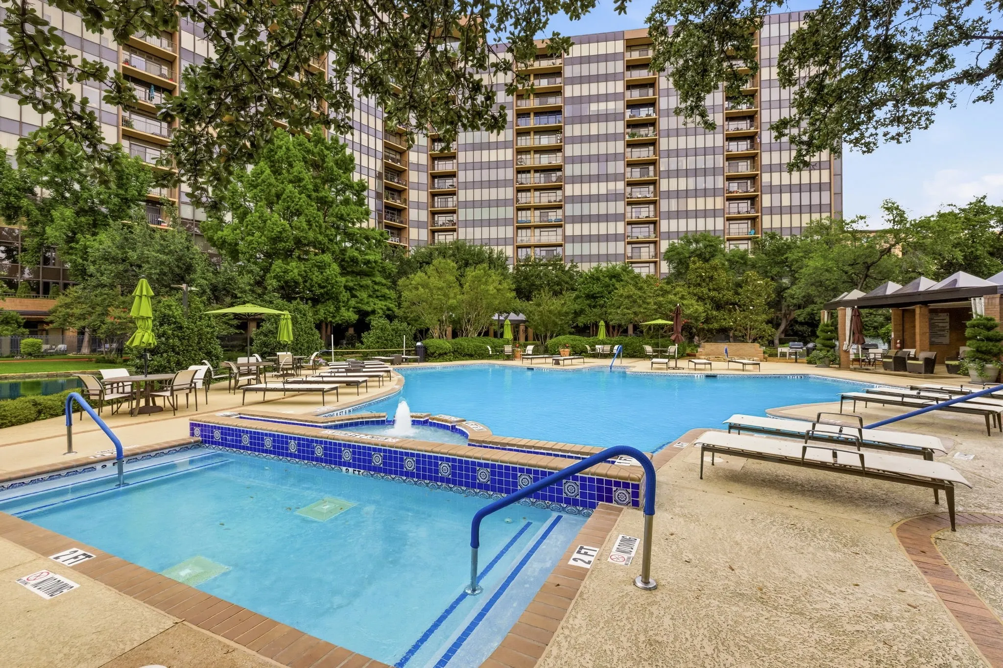 Expansive outdoor pool area featuring a large swimming pool, an integrated spa with a water feature, and a surrounding concrete deck