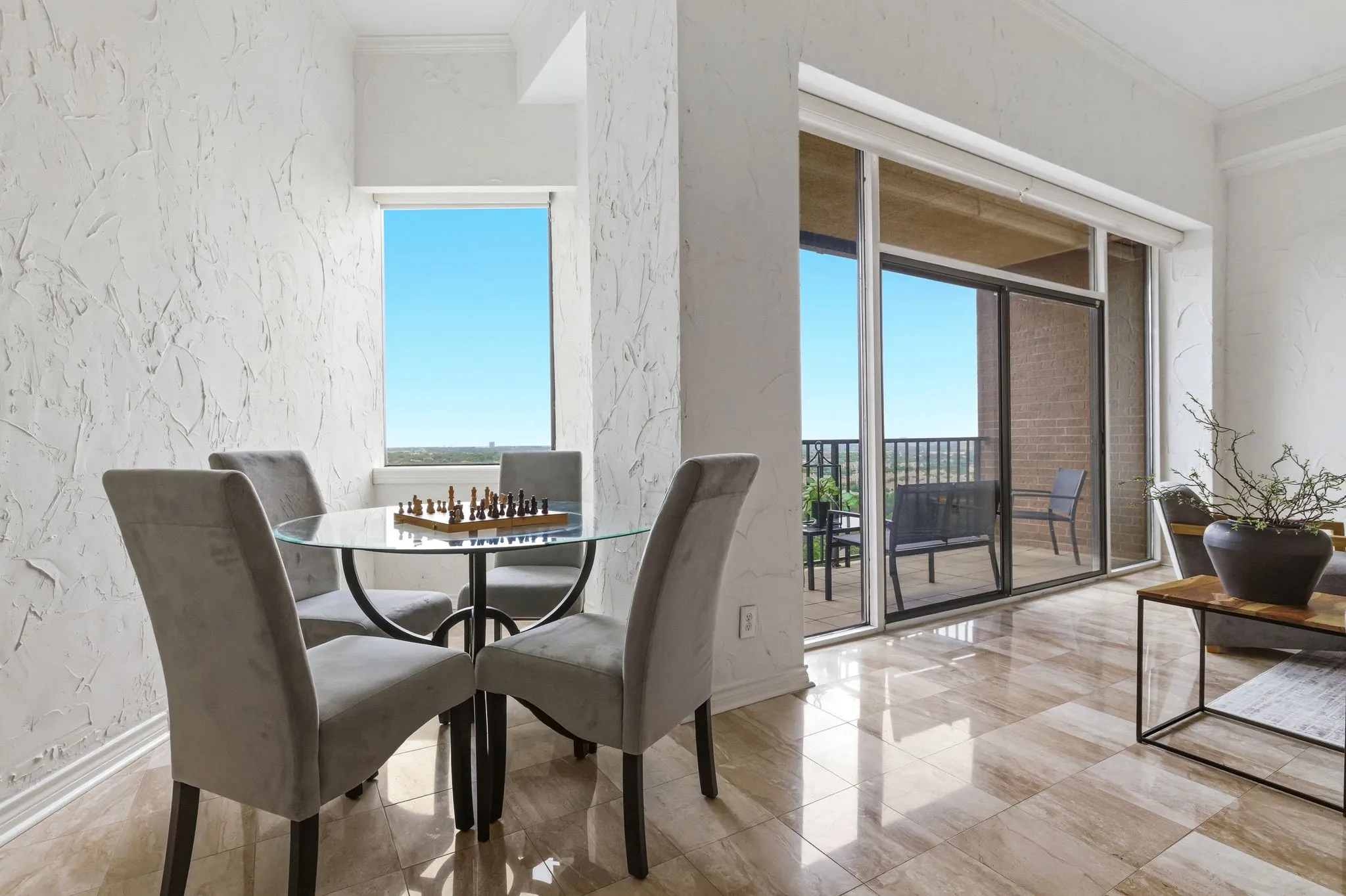 Dining area featuring a glass-top table, textured walls, and high-gloss tile flooring