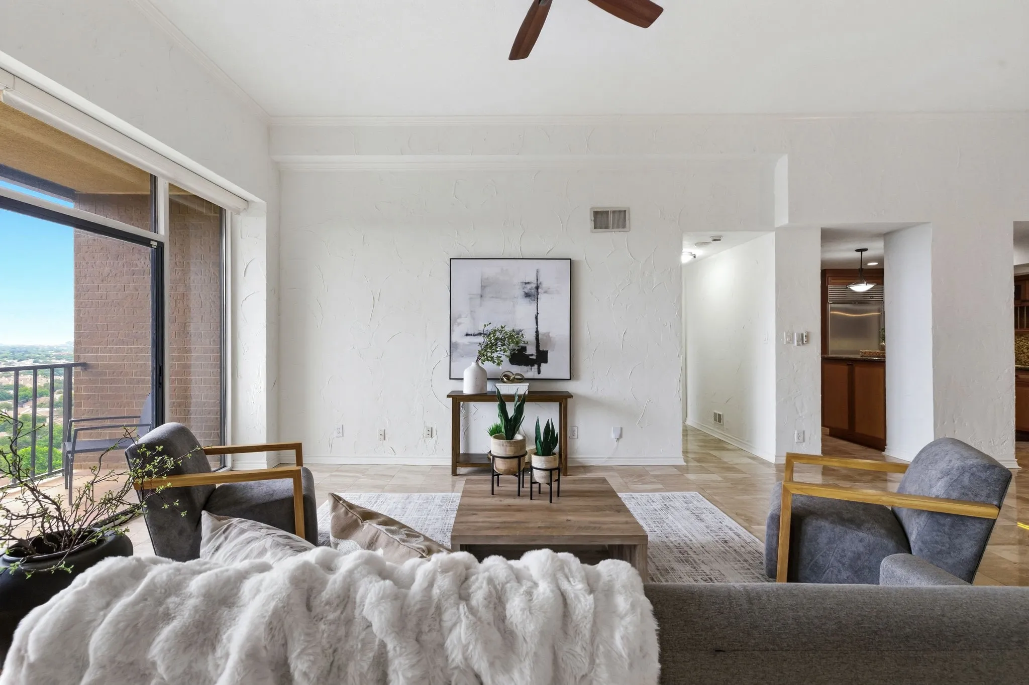 Spacious living area featuring light-colored textured walls, crown molding, and wood-finish flooring