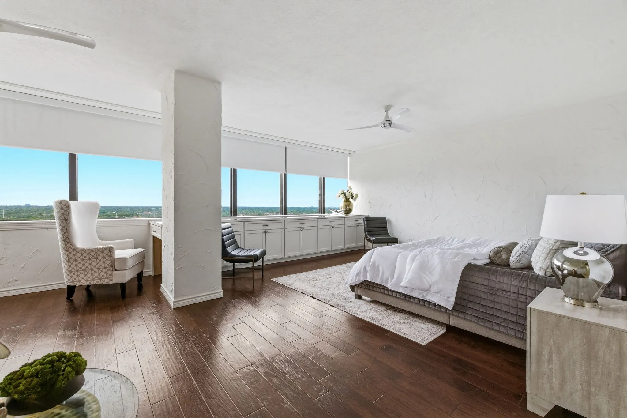 Expansive room featuring dark wood-finish flooring, a white textured wall finish, and a ceiling fan