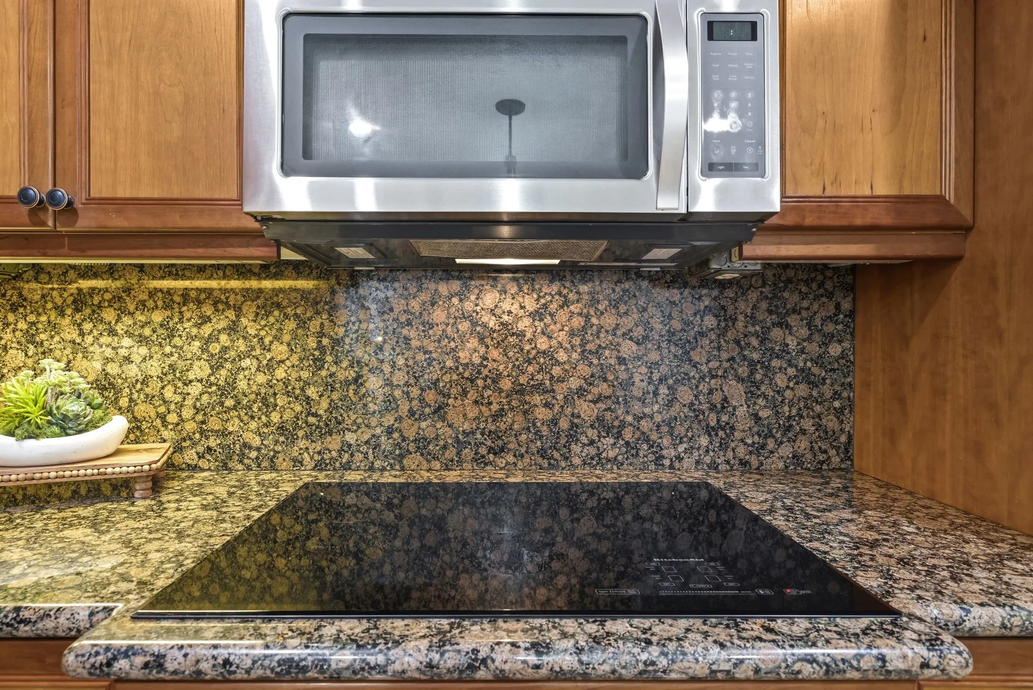 Stainless steel microwave over a flush-mounted black glass cooktop
