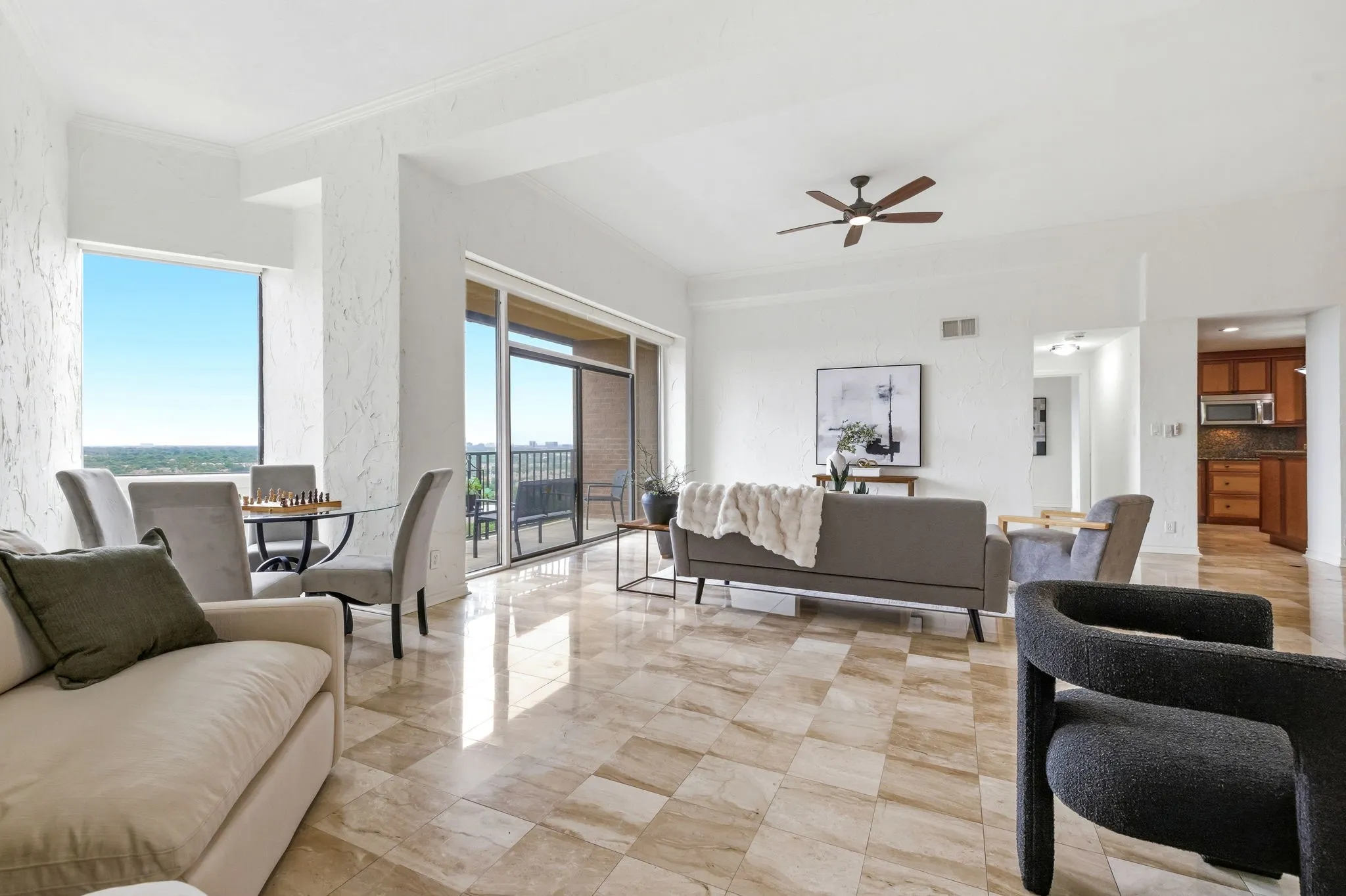 Open concept living space featuring large format tiled flooring, floor-to-ceiling windows, and a sliding glass door leading to a balcony