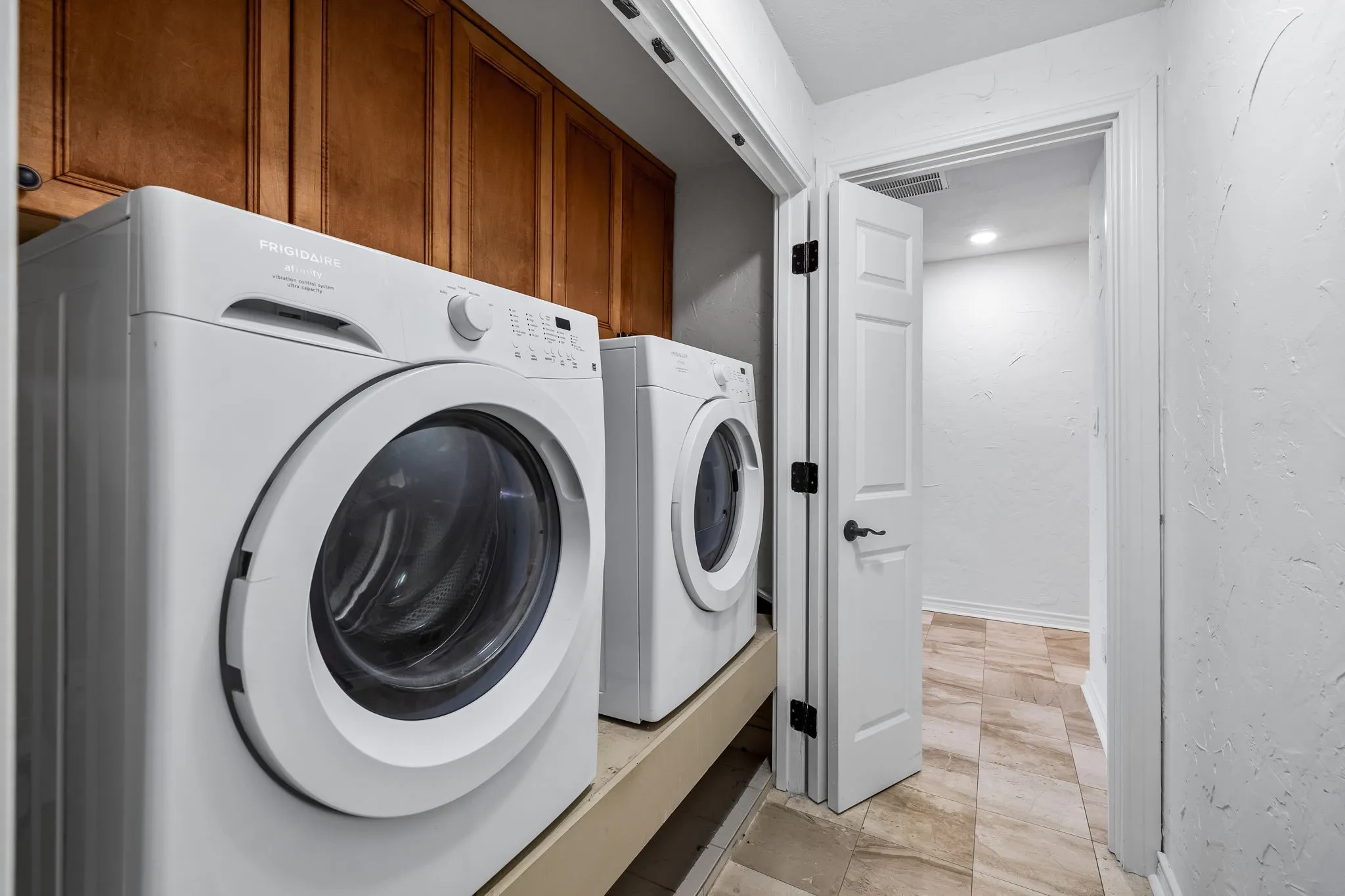 Laundry area featuring wood-finish cabinetry, a white washer and dryer, and recessed lighting