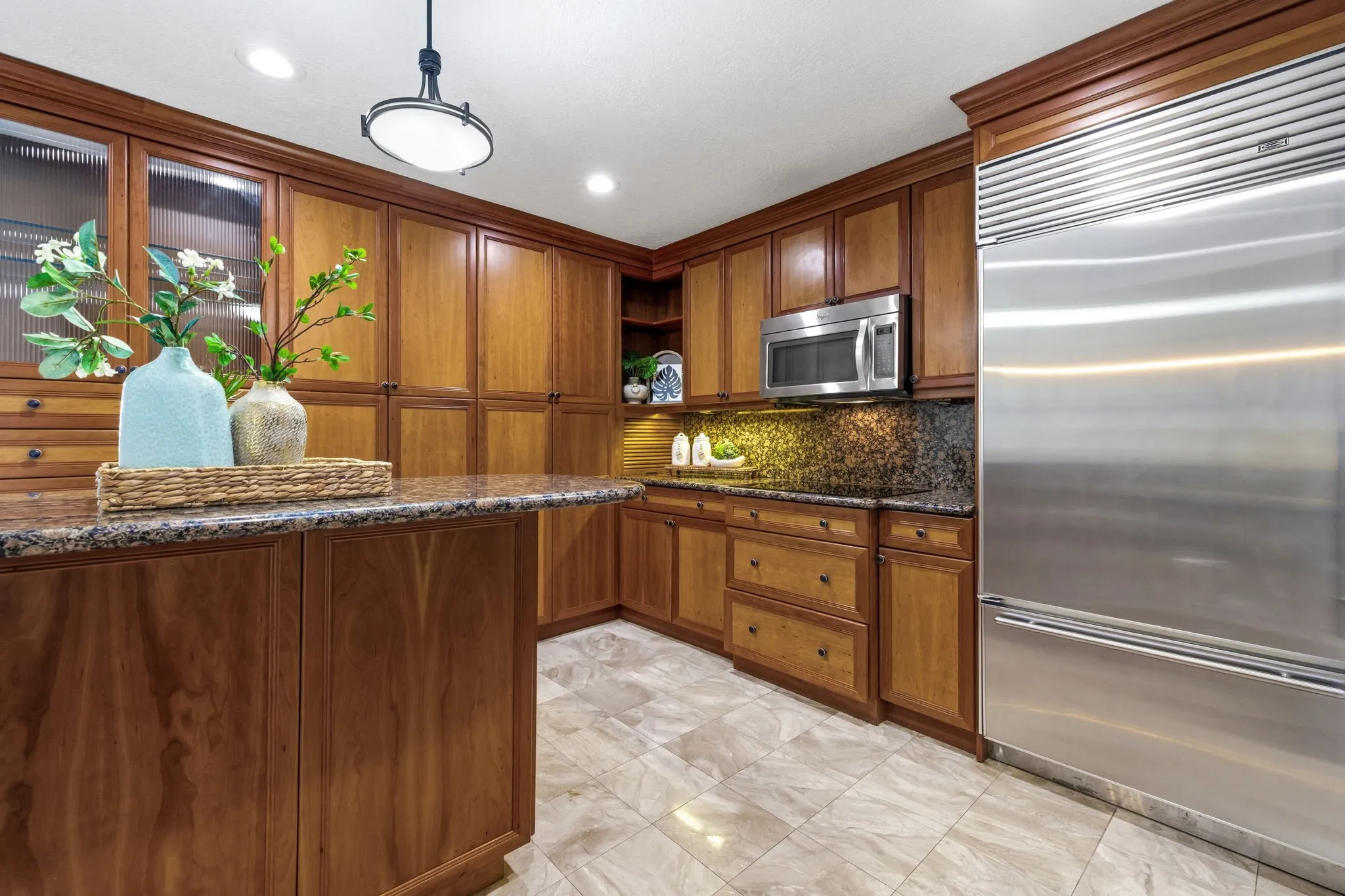 Kitchen featuring extensive wood cabinetry, granite countertops, tile flooring, and integrated stainless steel appliances