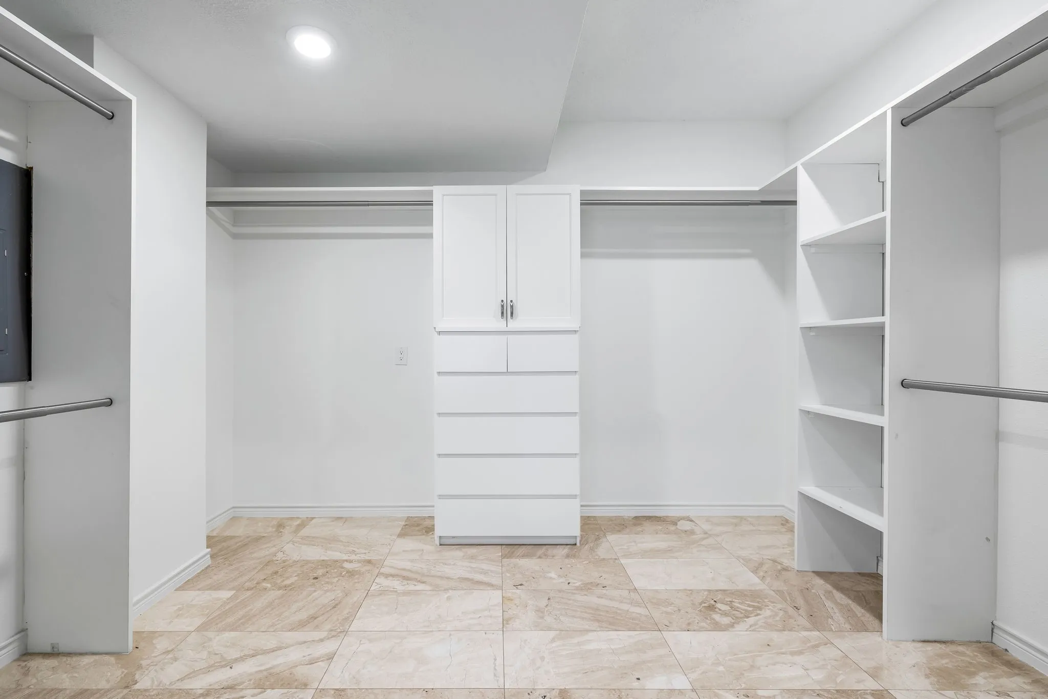Spacious custom closet featuring extensive built-in cabinetry, shelving, and hanging rods