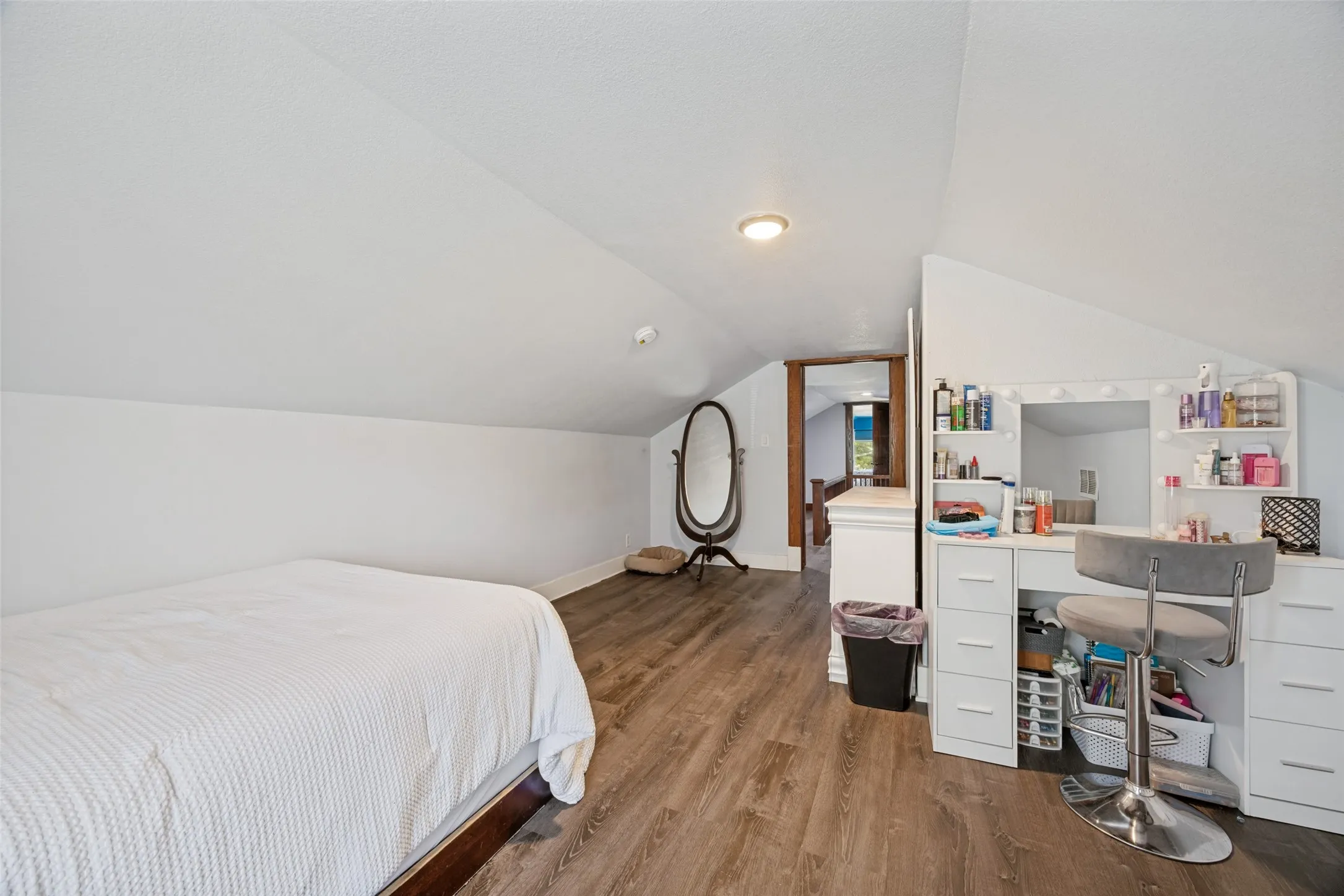 Room featuring wood-finish flooring, sloped ceilings, white walls, and recessed lighting