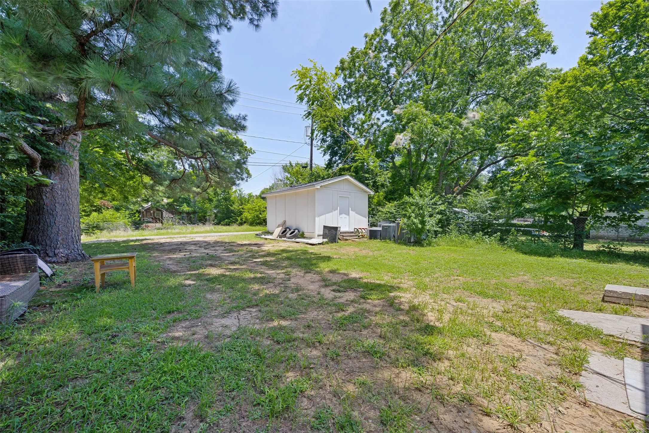 Spacious backyard featuring a white storage shed and mature trees