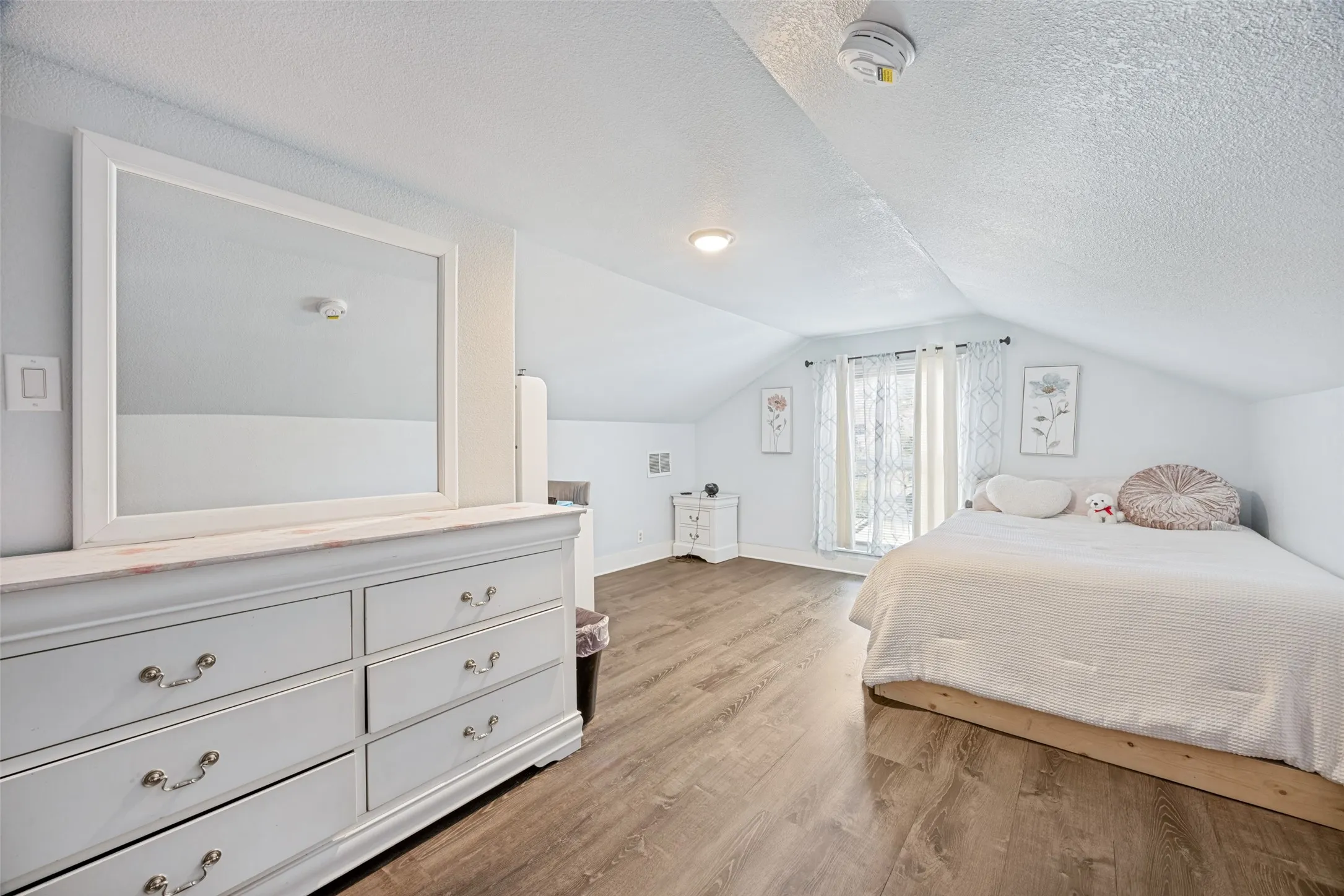 Spacious room with wood-finish flooring, bright white walls, and a recessed window
