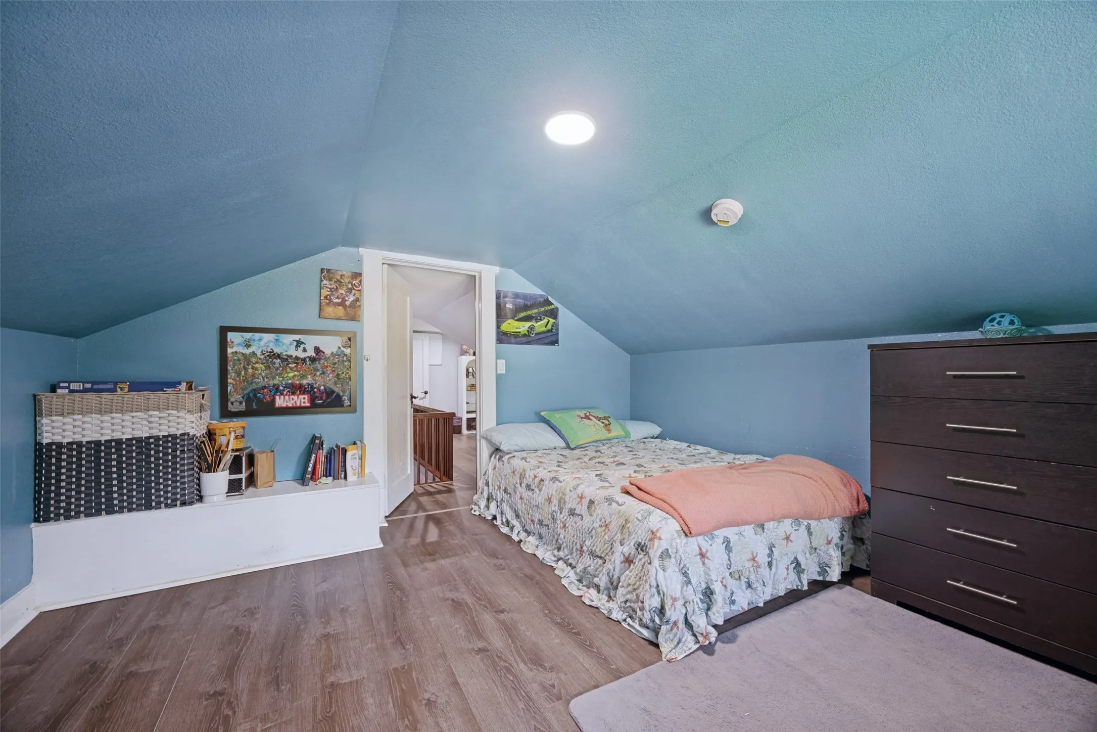 Sloped ceiling room featuring wood-finish flooring, recessed lighting, and a built-in low wall shelf