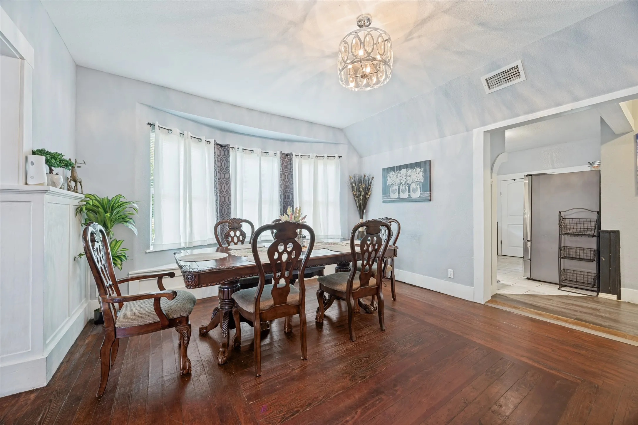 Interior dining space featuring wood-finish flooring, a curved bay window, and a decorative chandelier