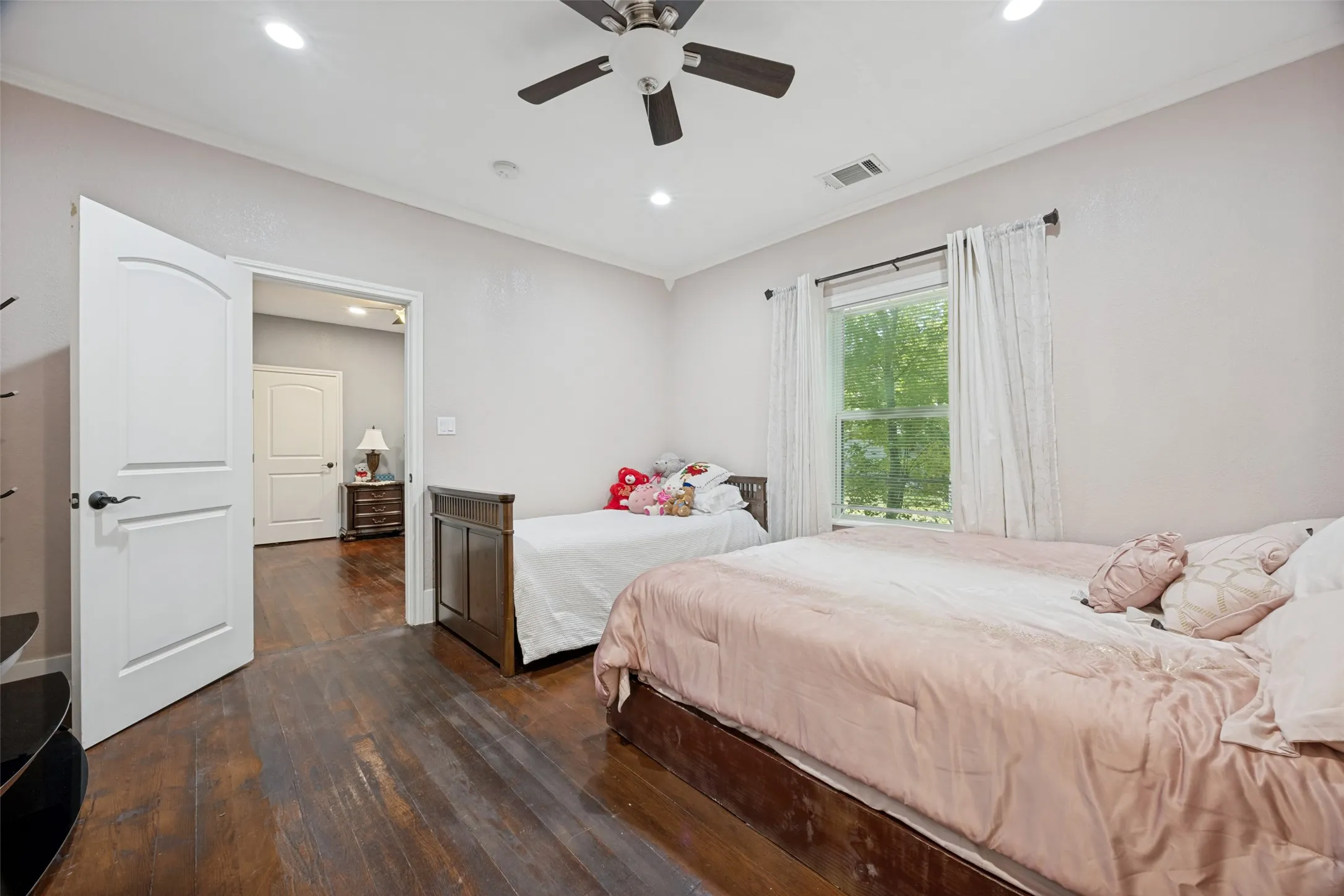 Spacious interior room featuring wood-finish flooring, a ceiling fan with integrated lighting, recessed lighting, and a window with exterior tree views