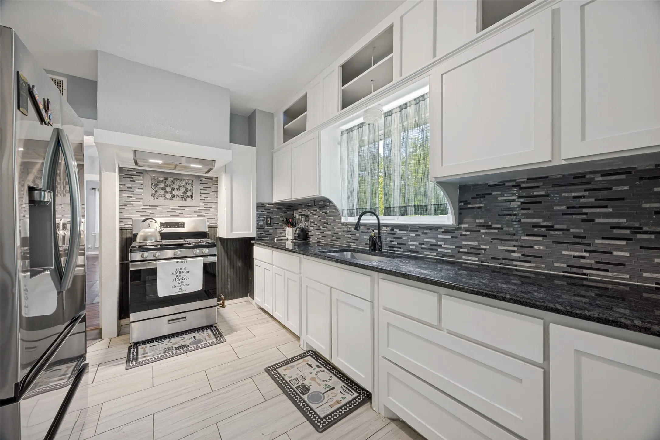 Kitchen featuring white shaker-style cabinetry, dark speckled countertops, and a mosaic tile backsplash