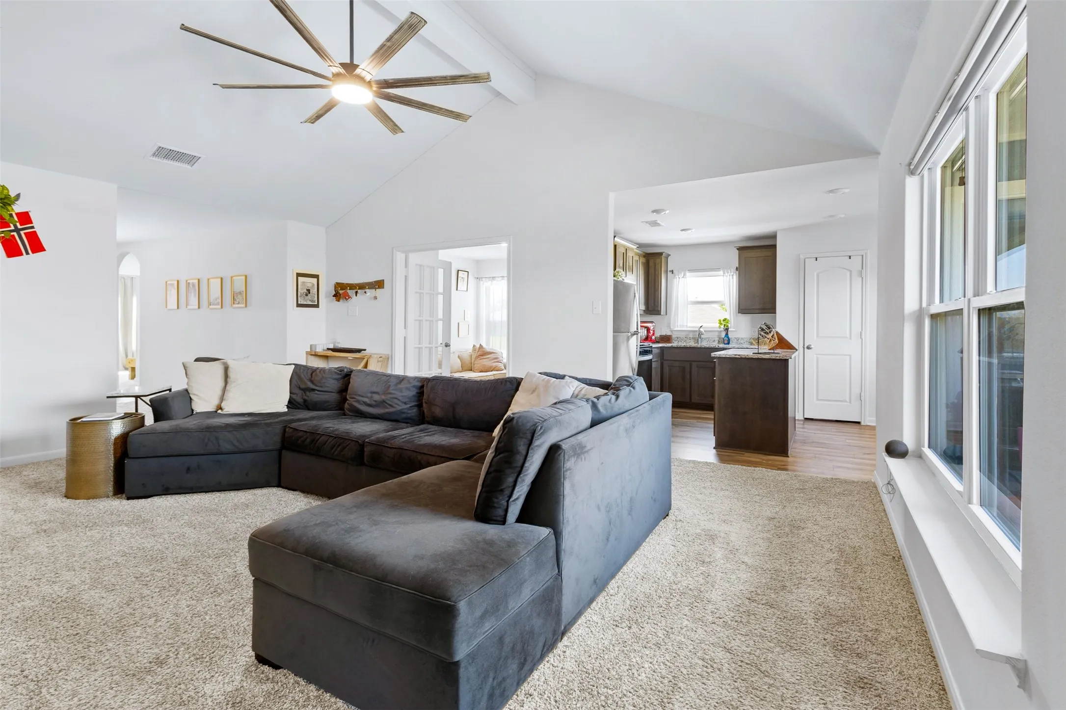 Spacious living area featuring a vaulted ceiling and a multi-blade ceiling fan