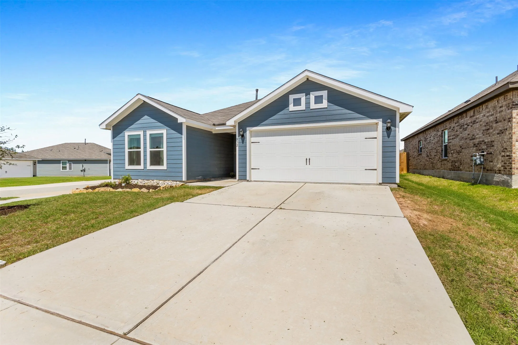 Contemporary single-story residence featuring blue siding, white trim, and a concrete driveway