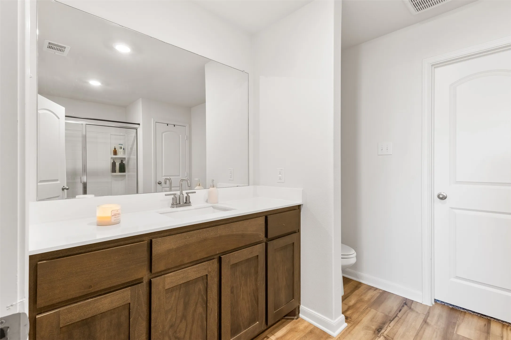 Bathroom vanity featuring a light wood-finish cabinet with multiple storage doors and drawers