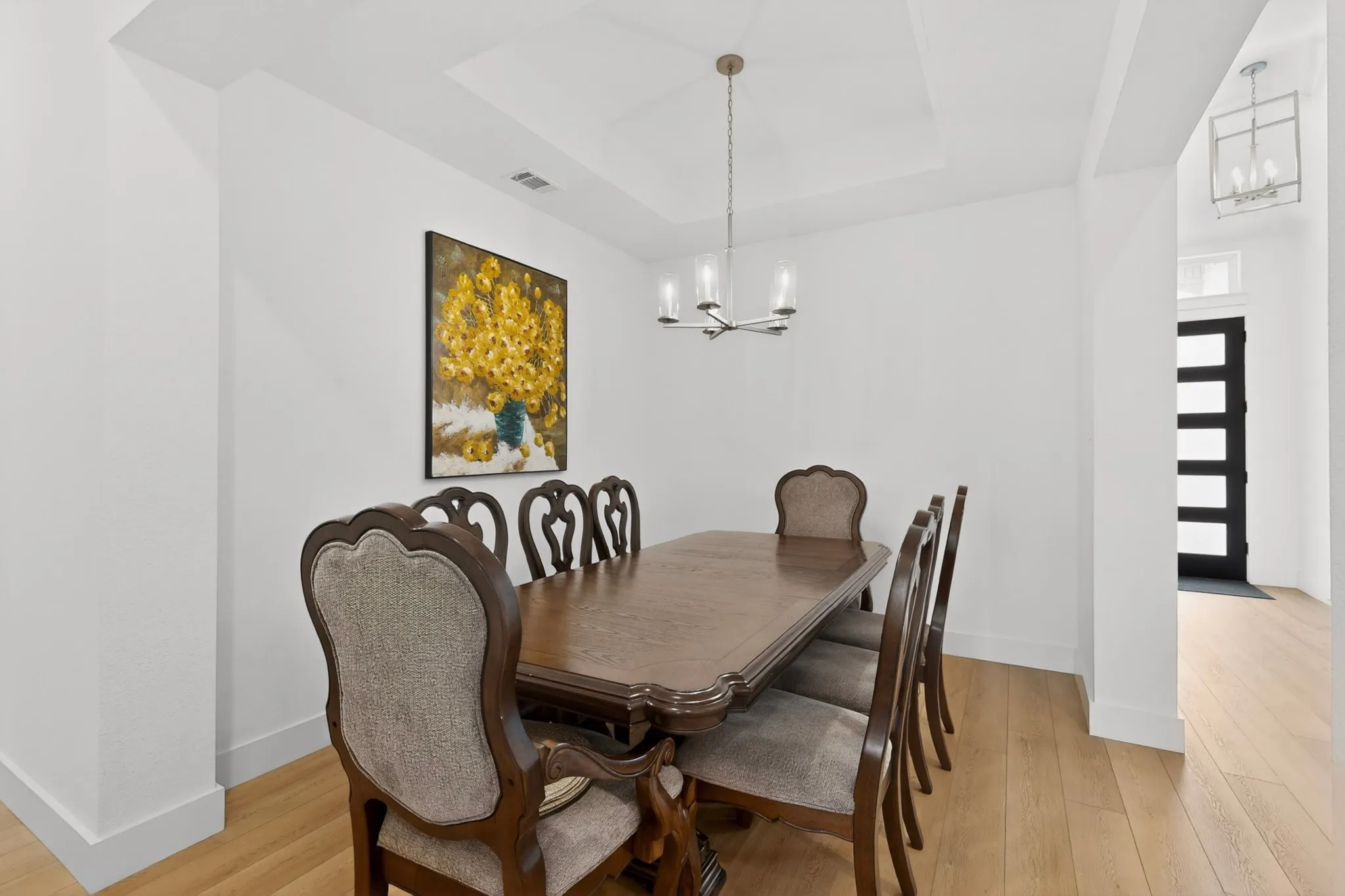 Dining area featuring a tray ceiling, a modern chandelier, and light wood-finish flooring