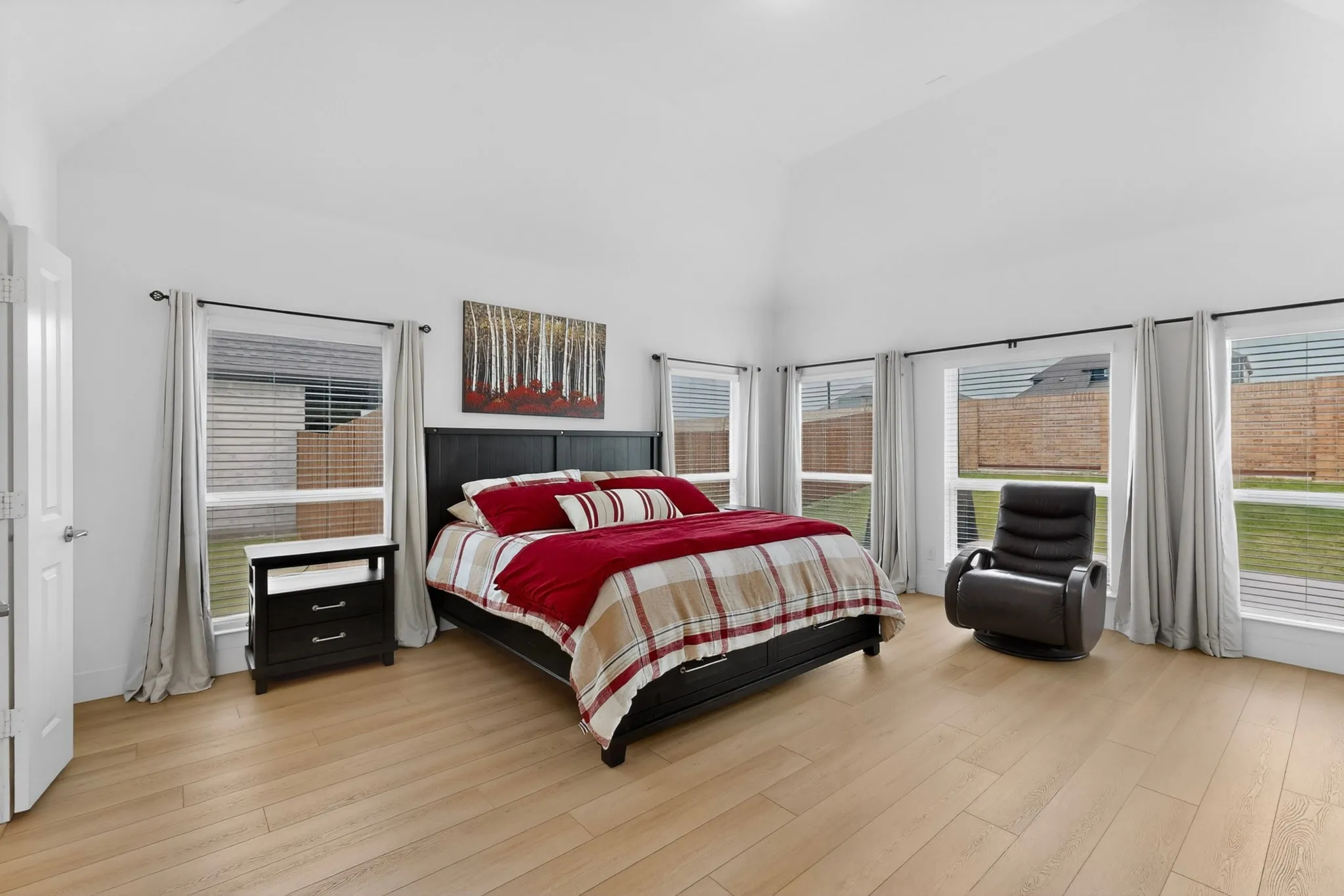 Spacious room featuring a vaulted ceiling and light wood-finish flooring