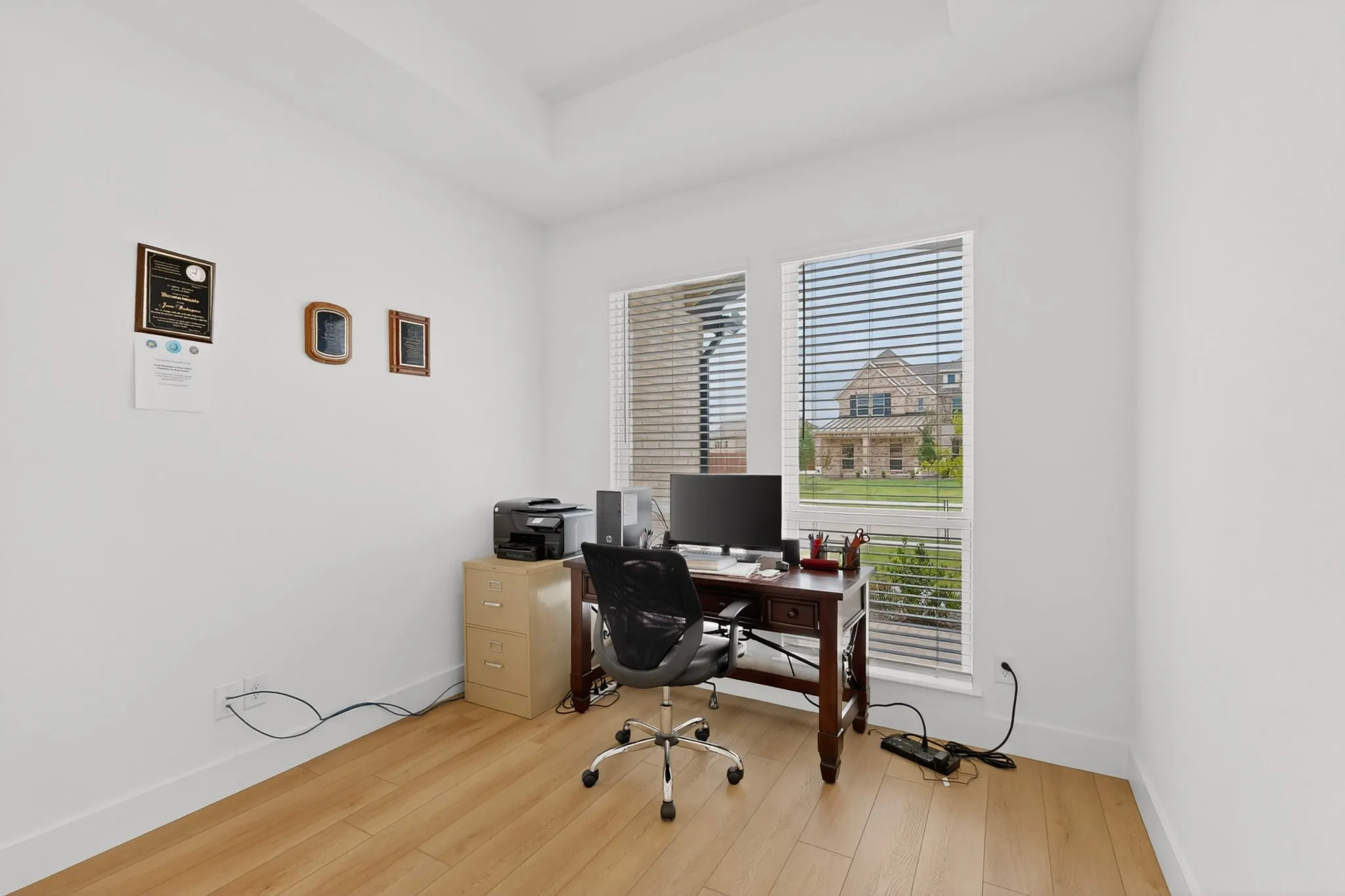 Bright room featuring light wood-finish flooring, white walls, and a tray ceiling detail