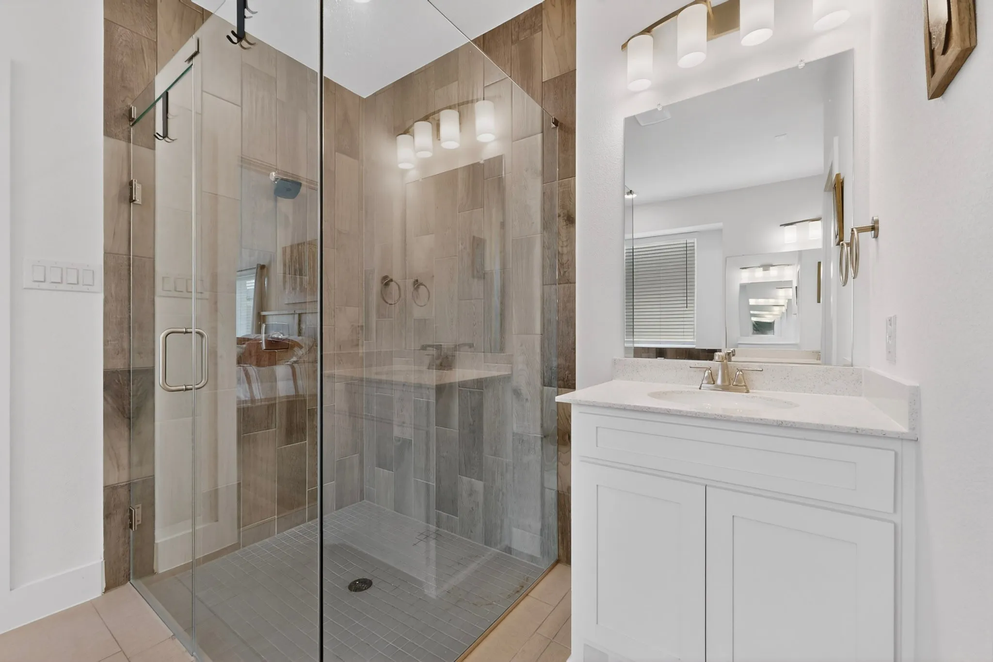 Glass-enclosed shower with wood-finish tile surround and a tiled floor