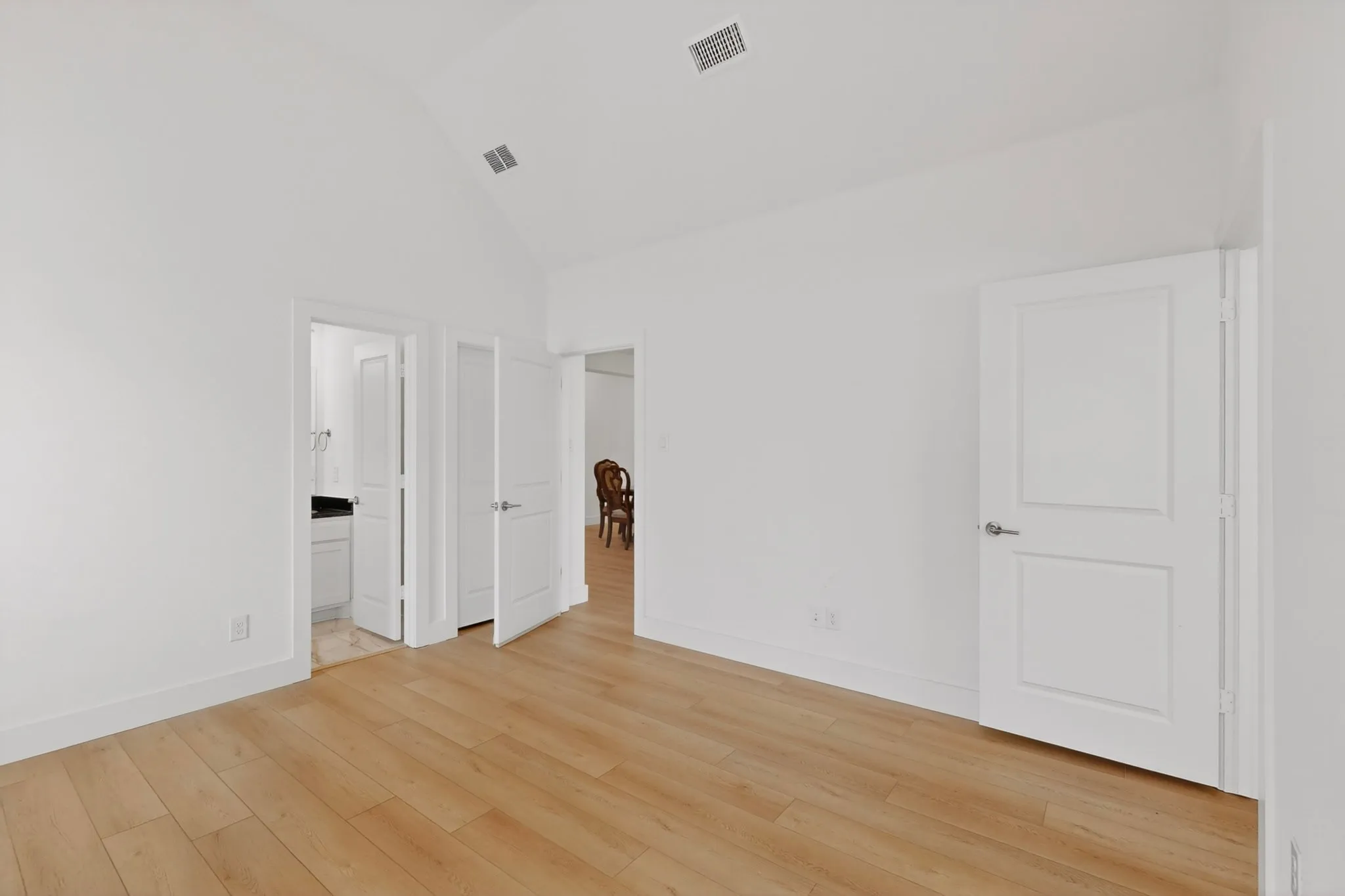 Spacious room with vaulted ceiling and light wood-finish flooring