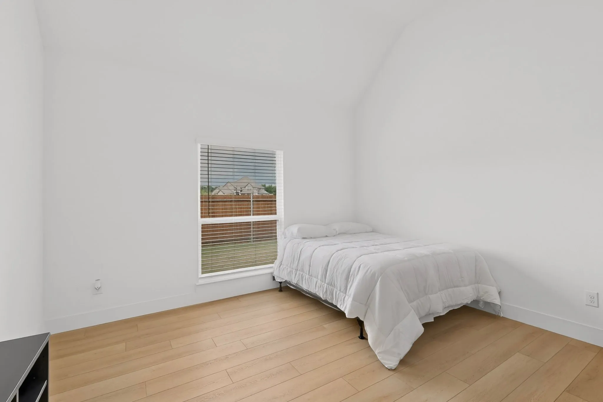 Bright room featuring a vaulted ceiling and wood-finish flooring