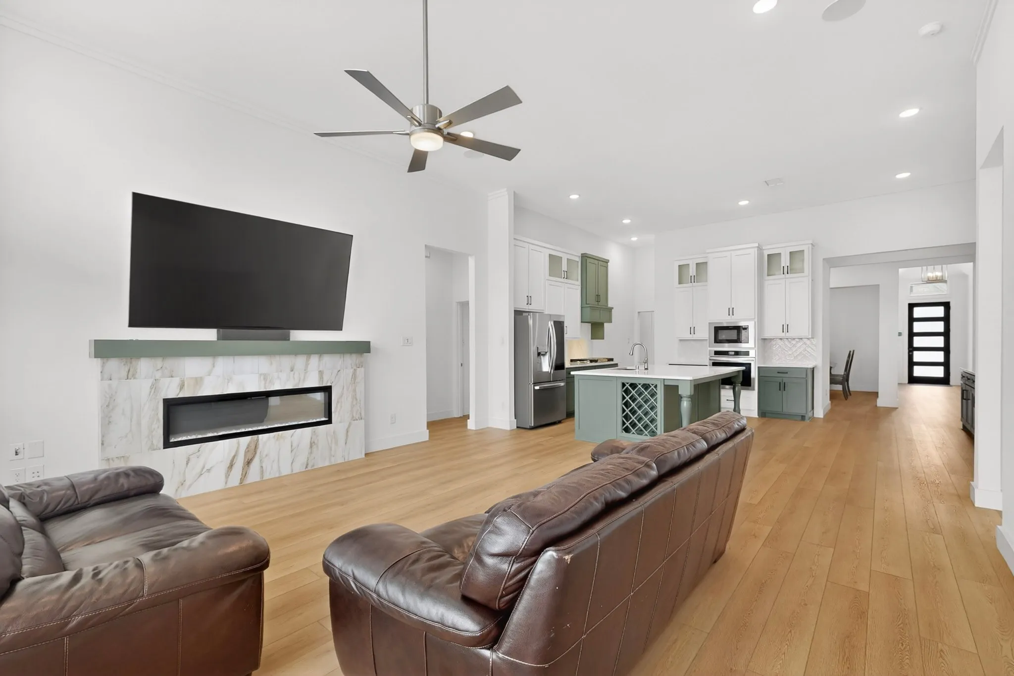 Spacious open-concept living area featuring wood-finish flooring, recessed lighting, and a ceiling fan
