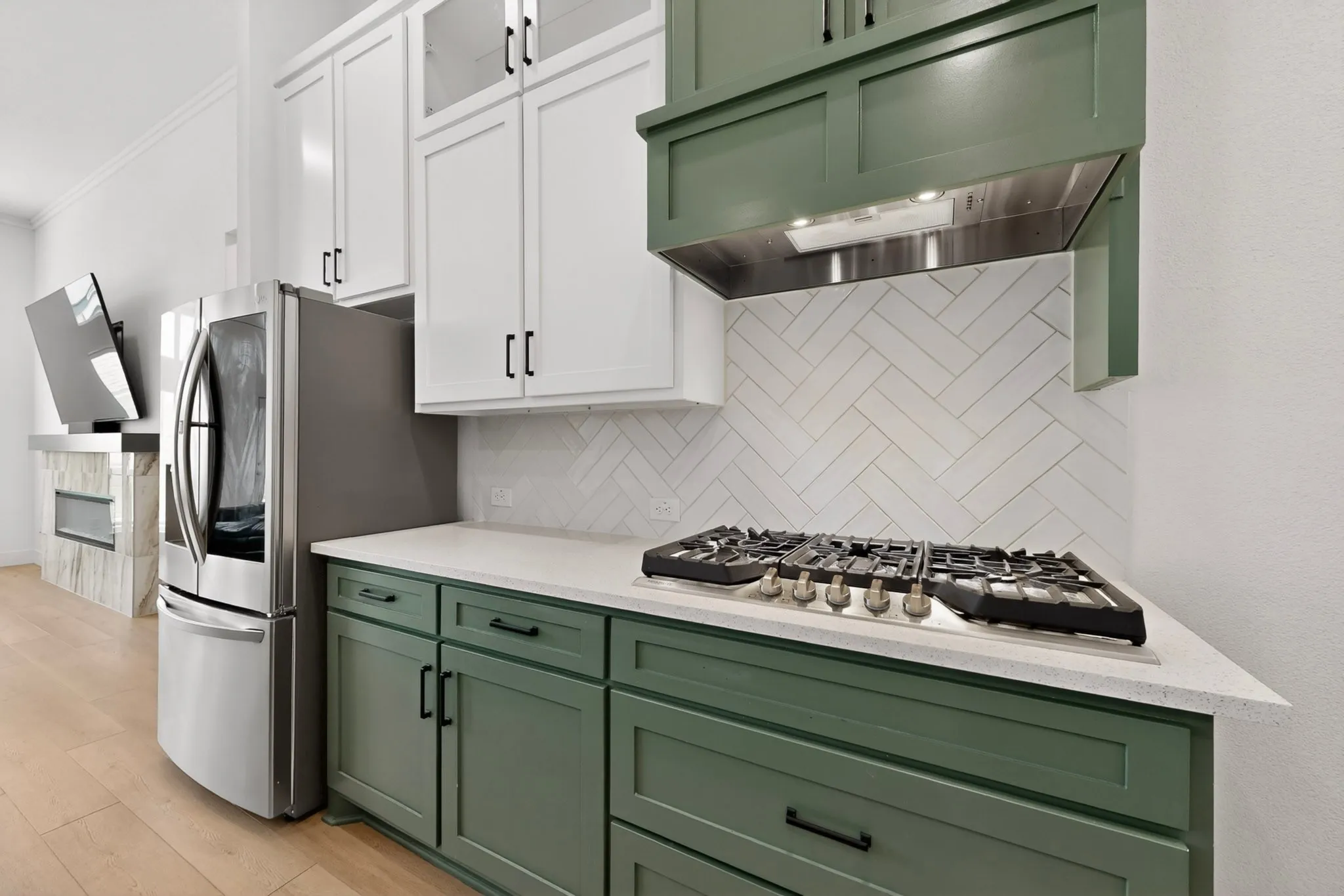 Kitchen featuring two-tone cabinetry with white upper cabinets and green lower cabinets, complemented by a white herringbone tile backsplash