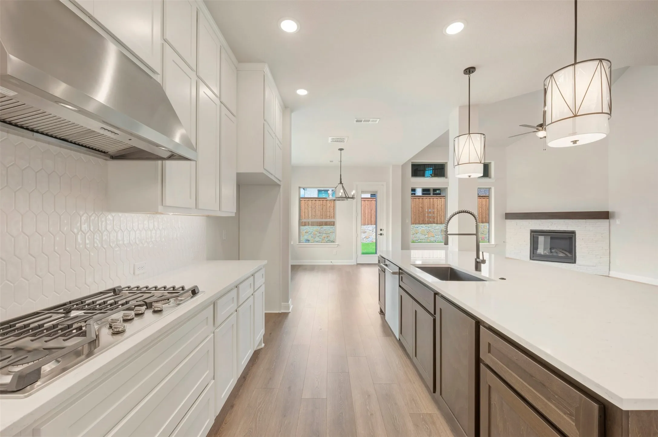 Kitchen features a gas range with stainless steel hood, white cabinetry, and a hexagonal tile backsplash