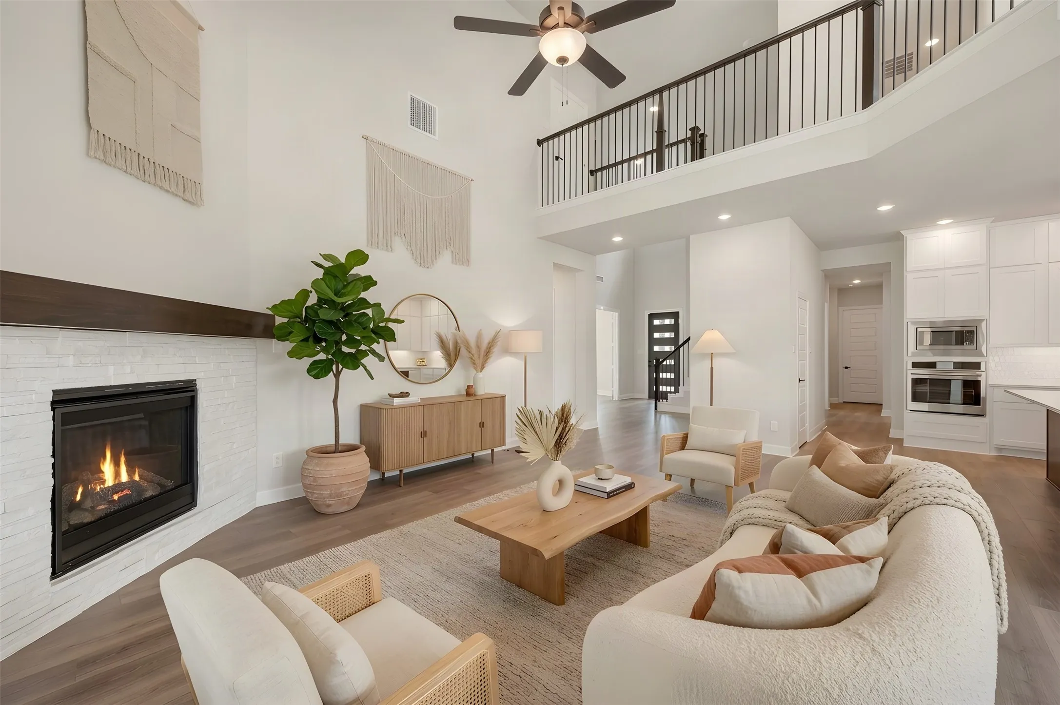 Vaulted ceilings with a ceiling fan, white brick fireplace with a dark wood mantel, wood-finish flooring, and an open-concept layout