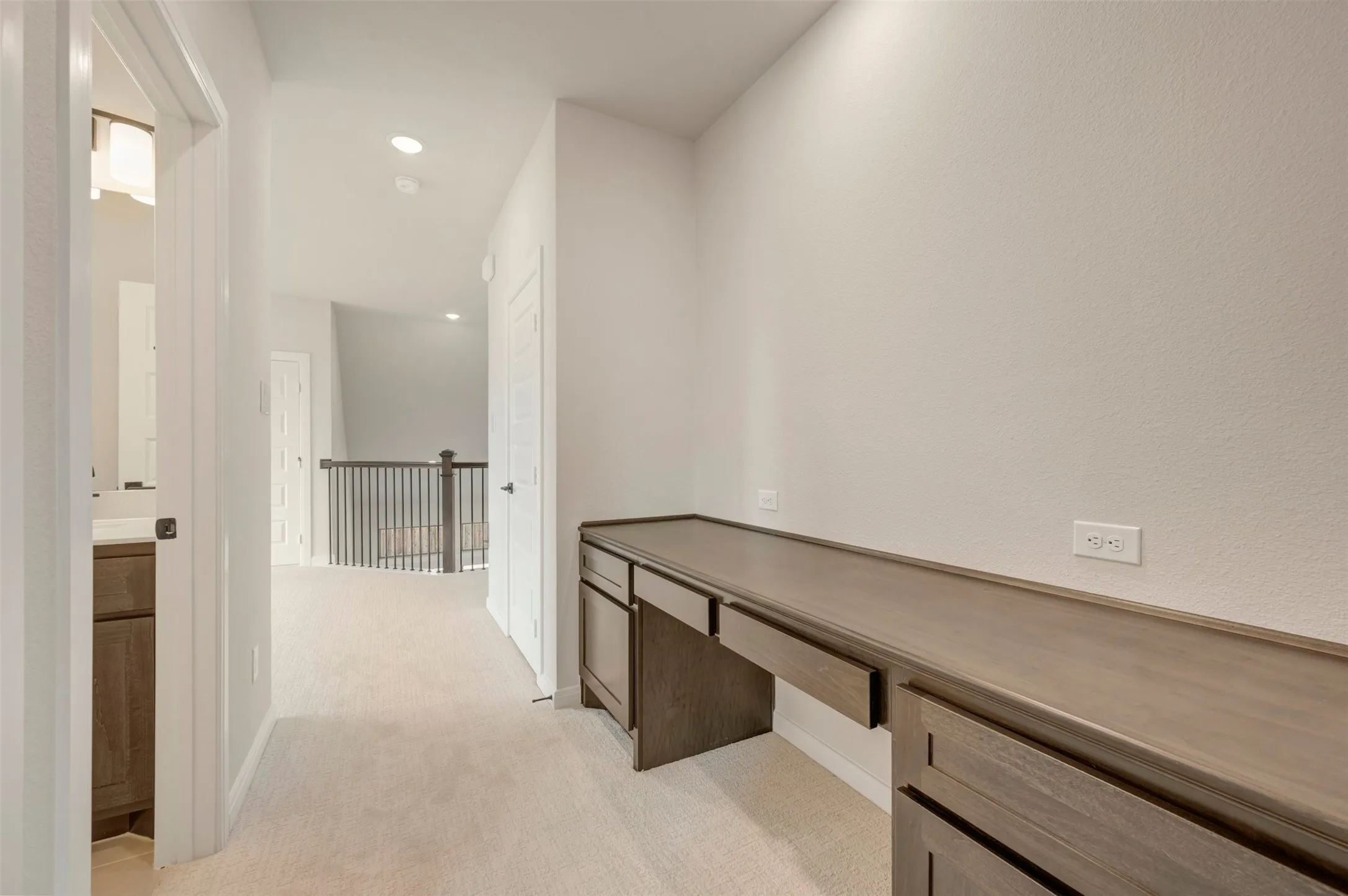Built-in wood-finish desk with drawers, carpeted flooring, and recessed lighting