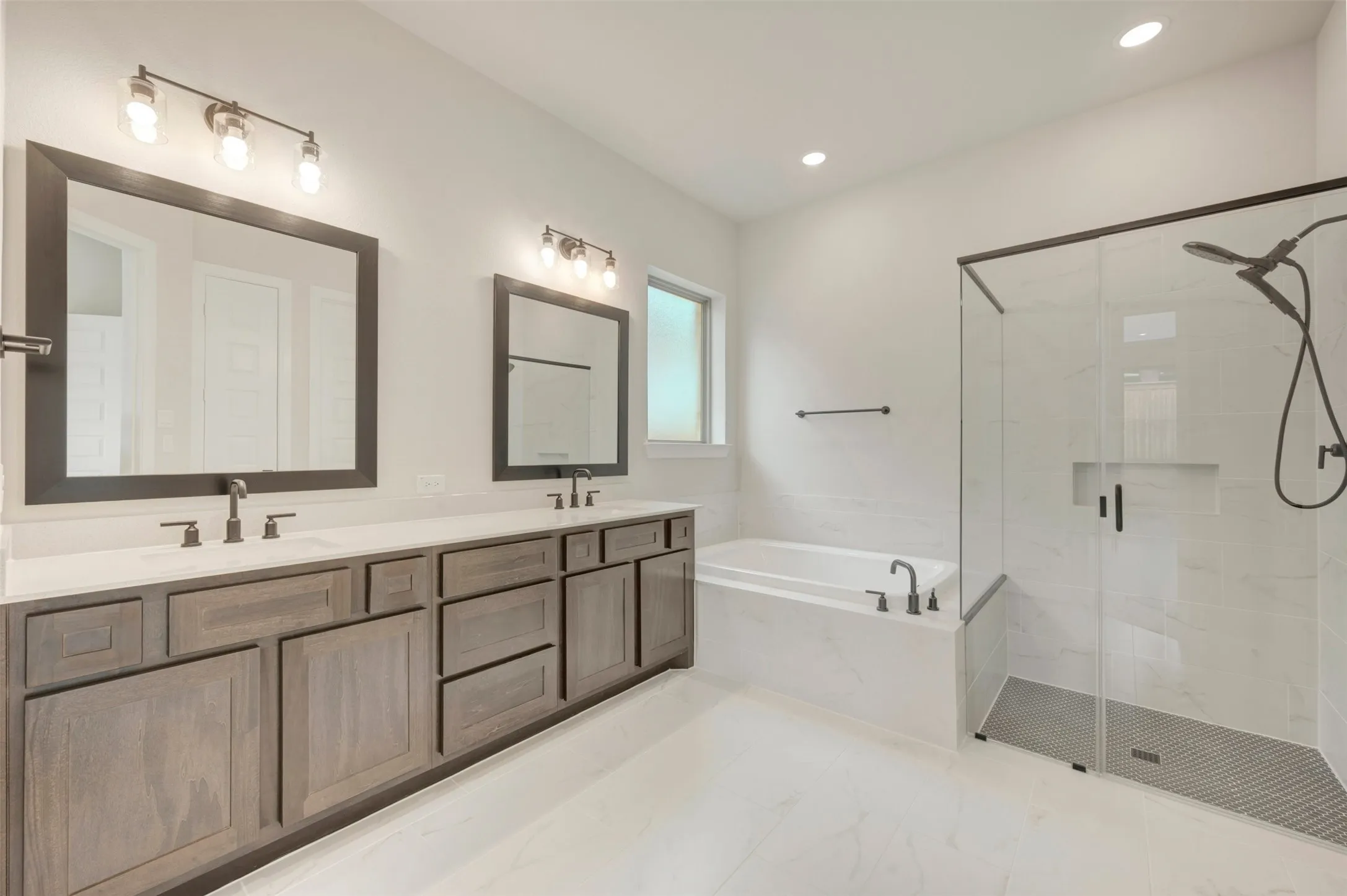 Dual vanity with wood-finish cabinetry, white countertops, and framed mirrors