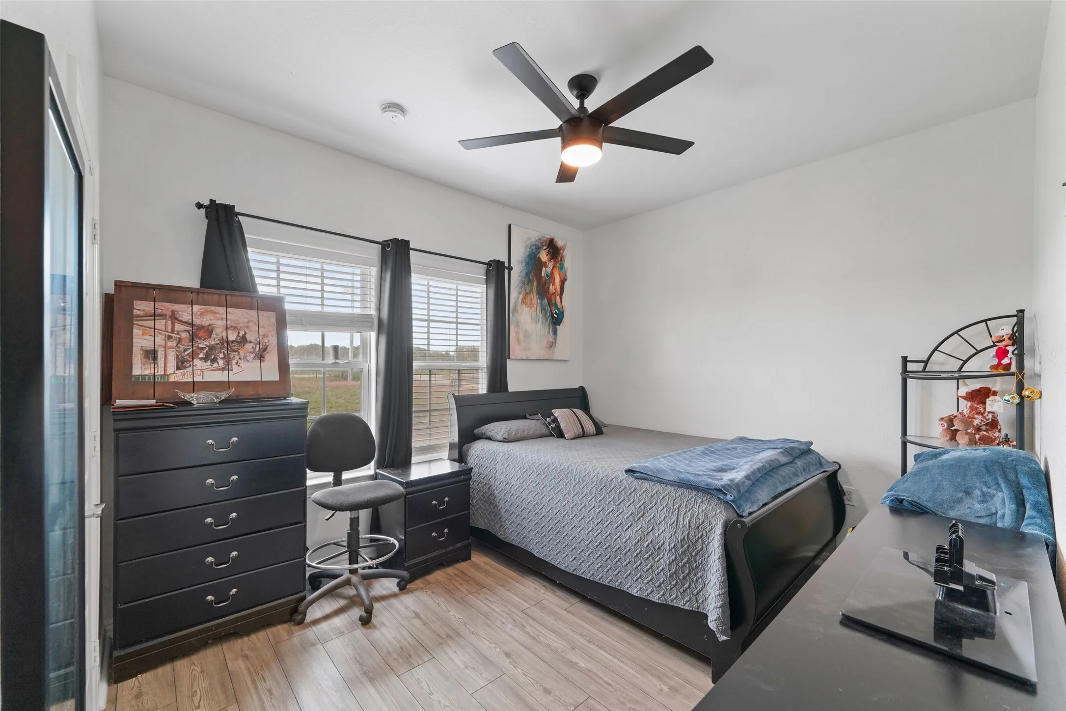Spacious room featuring wood-finish flooring, white walls, and a ceiling fan with integrated lighting