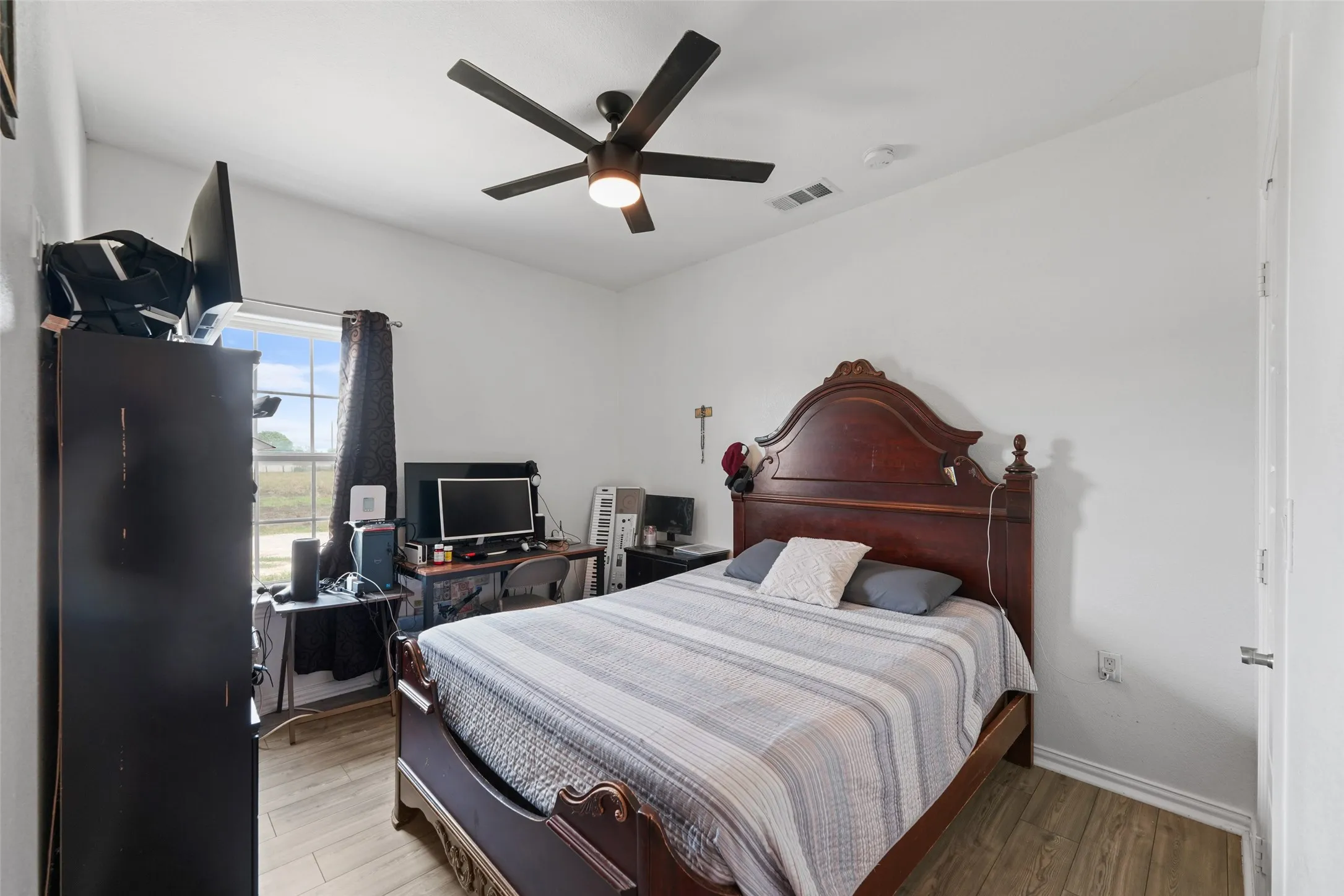 Room featuring wood-finish flooring, a window with exterior views, and a ceiling fan with integrated lighting