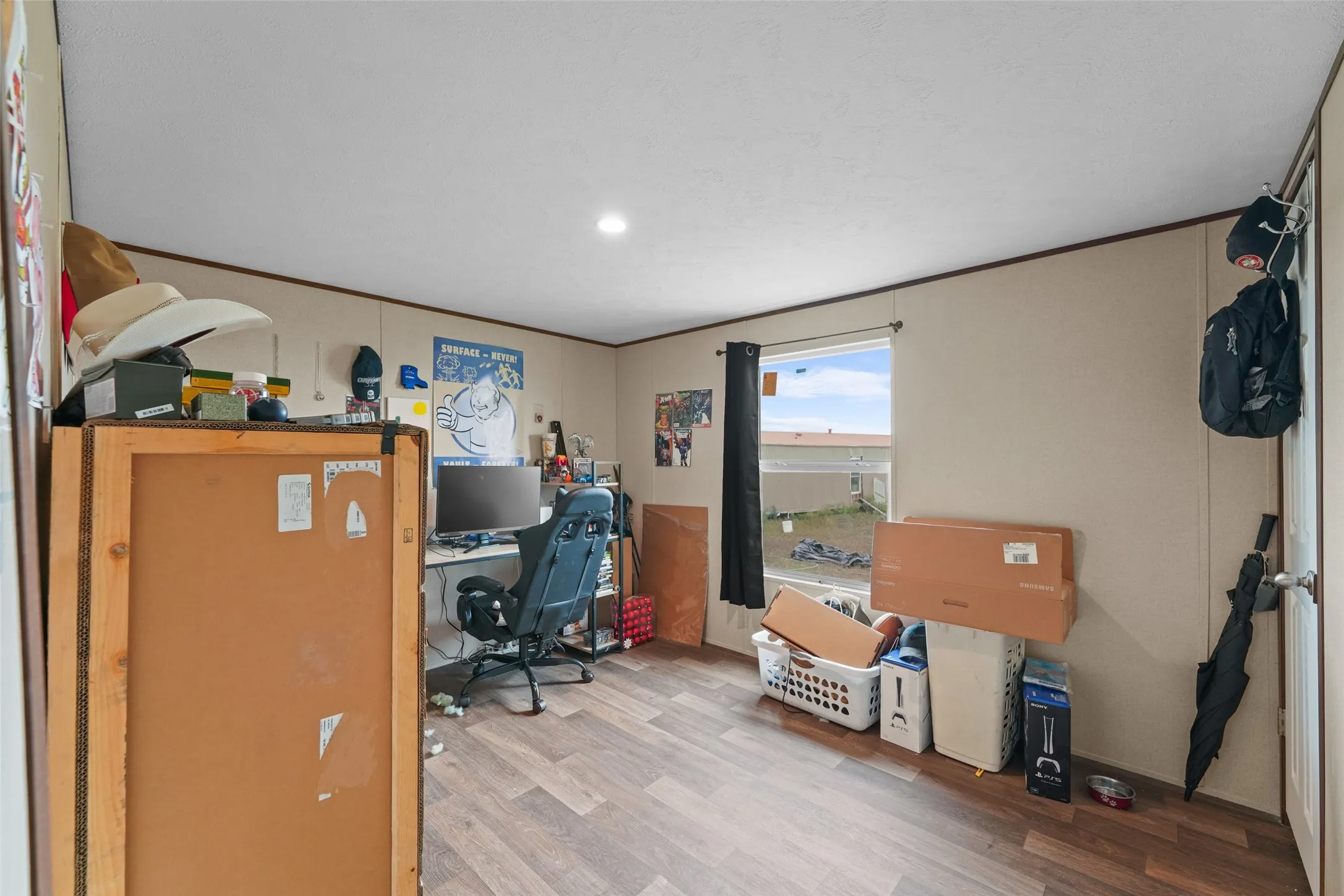 Interior room featuring wood-finish flooring, light-toned wall paneling, and a single window