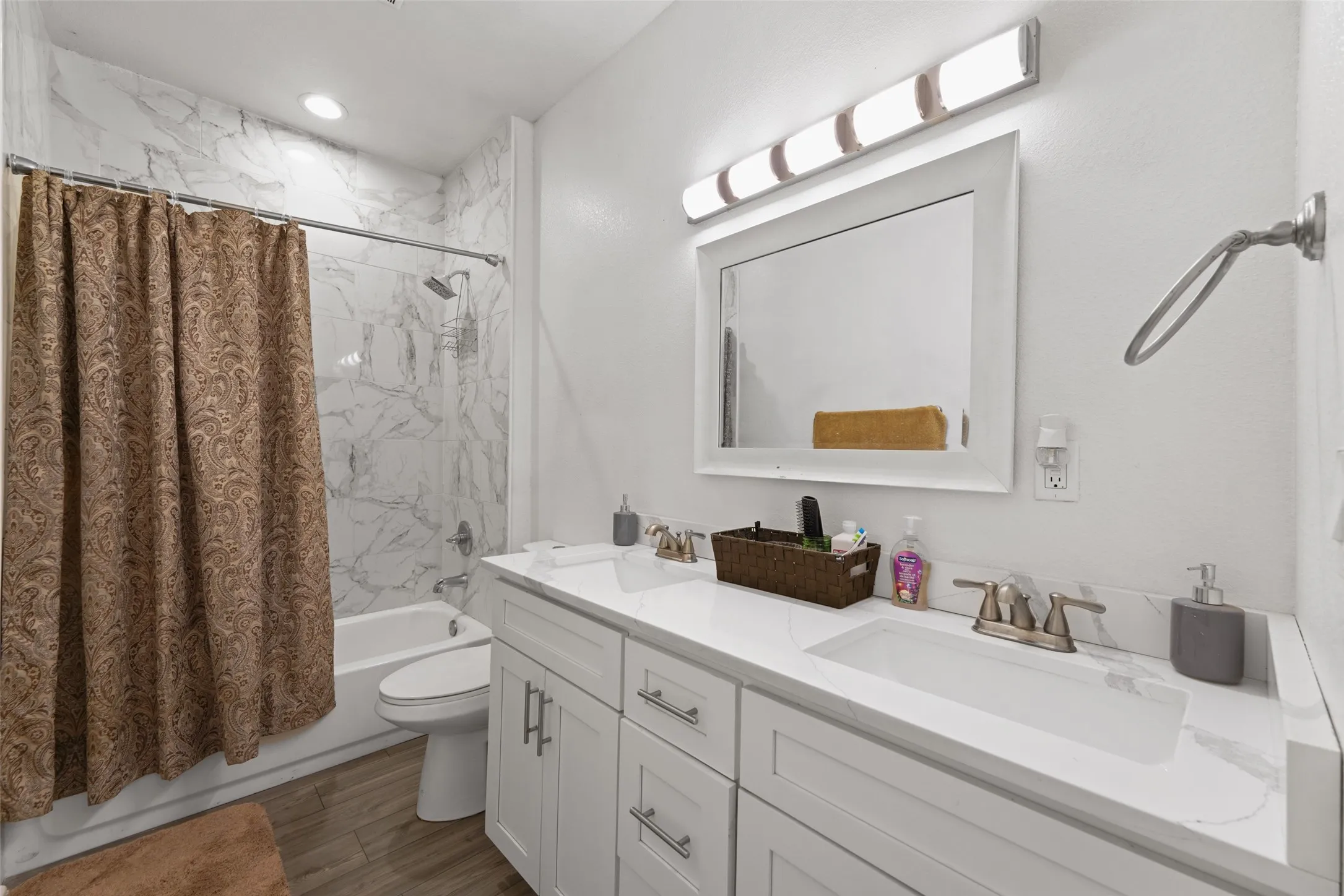 Bathroom featuring a dual-sink vanity with white cabinetry, a light-colored countertop, and a white framed mirror