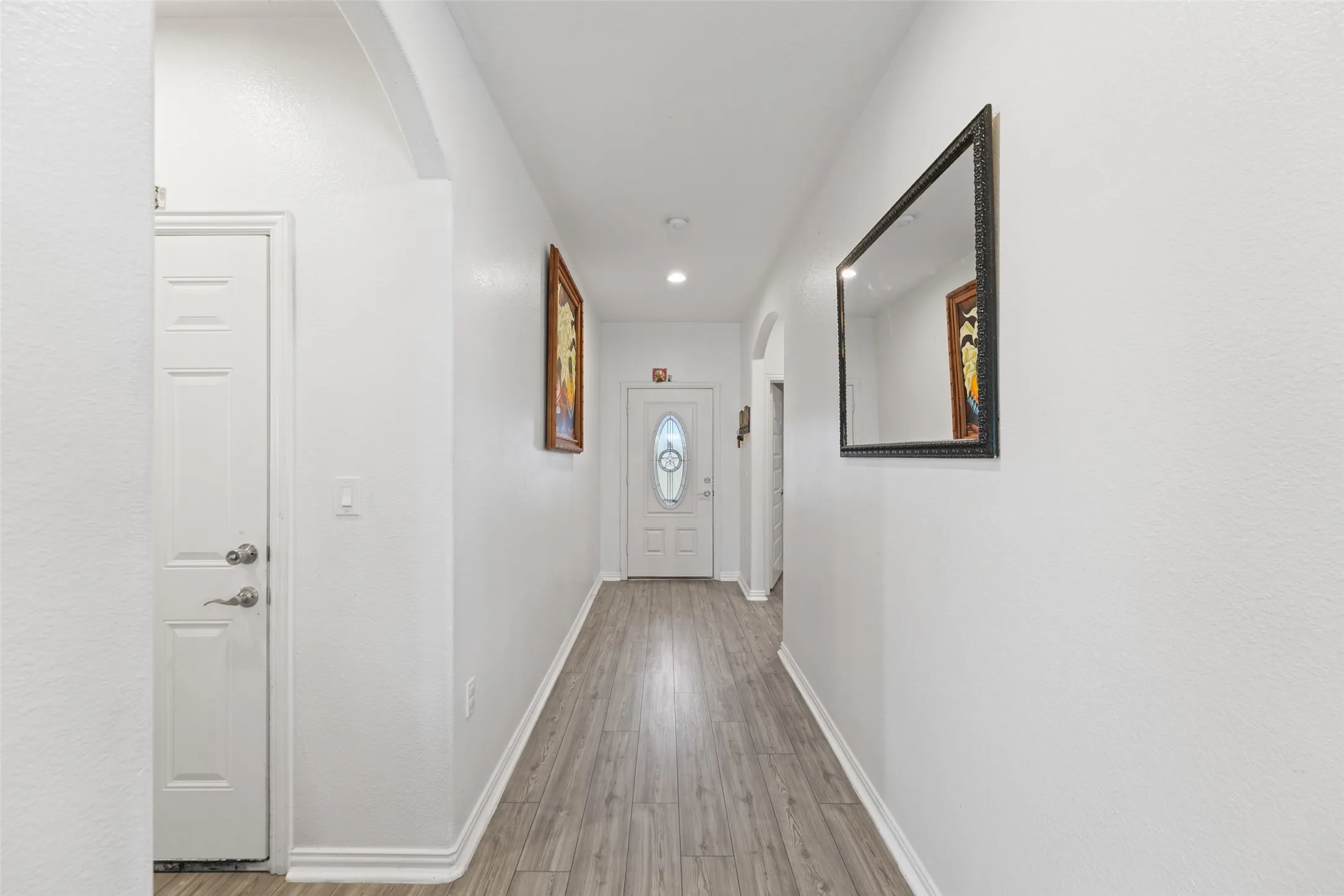 Bright hallway featuring wood-finish flooring, white baseboards, and recessed lighting