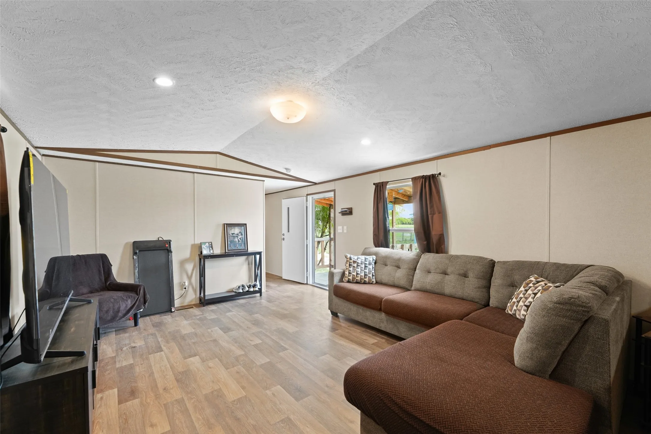 Spacious living area featuring wood-finish flooring, neutral wall tones, and recessed lighting