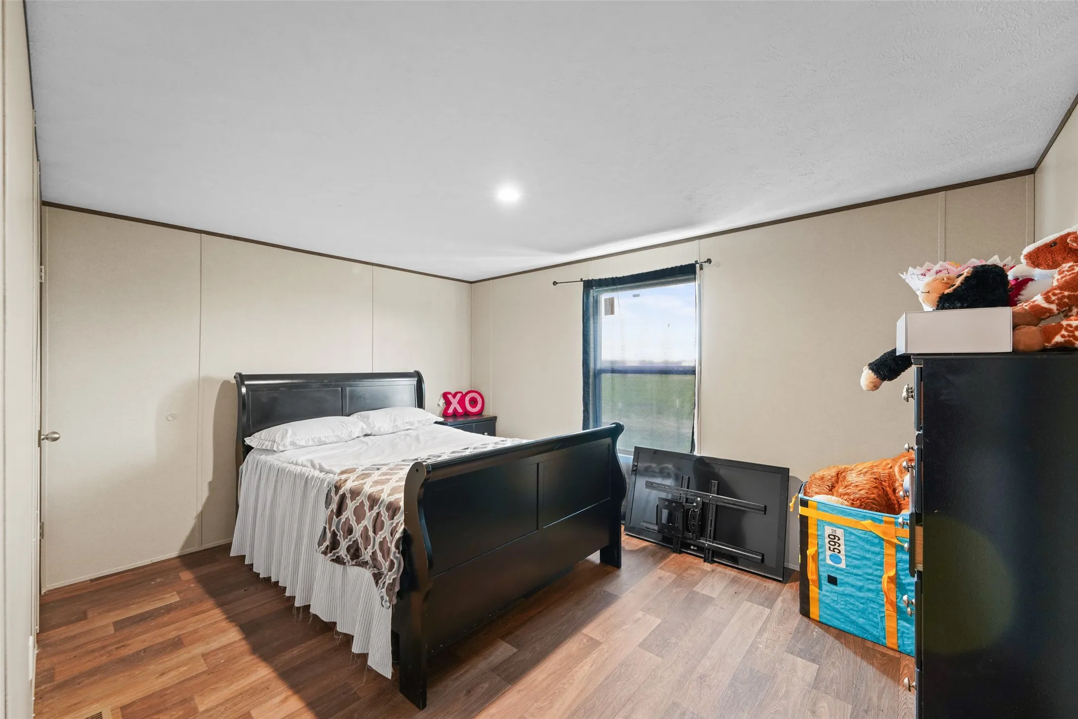 Room featuring wood-finish flooring, neutral wall paneling, and a single window