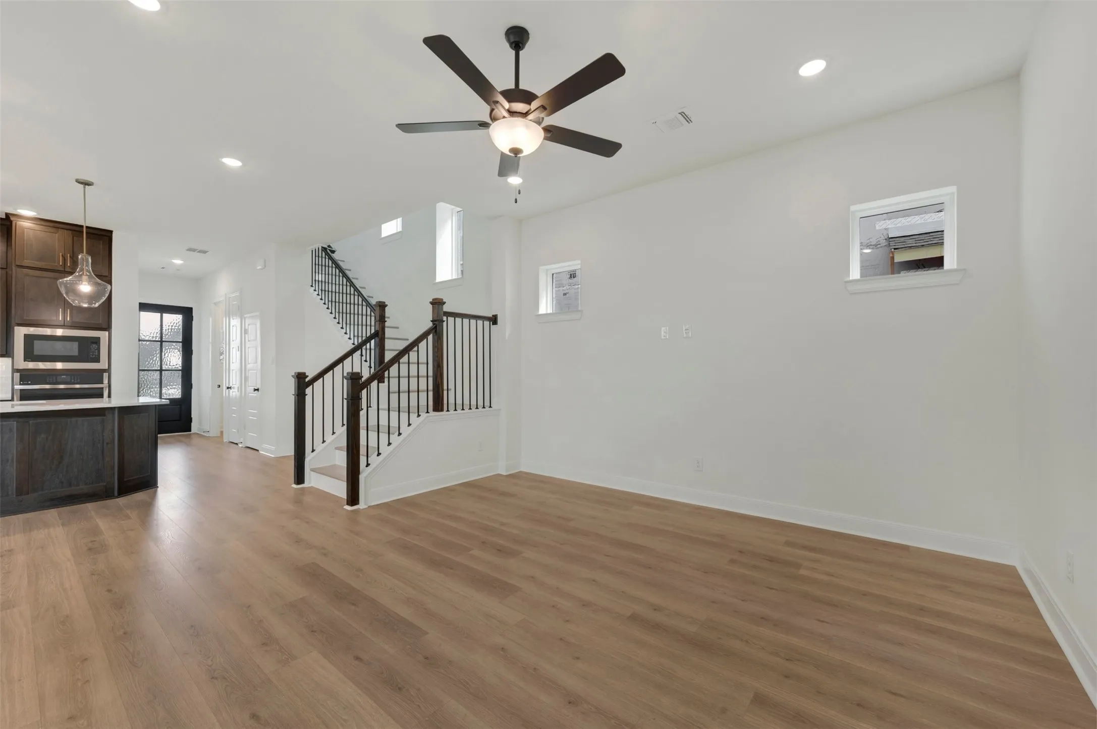 Open-concept living area featuring wood-finish flooring, recessed lighting, and a dark-toned ceiling fan