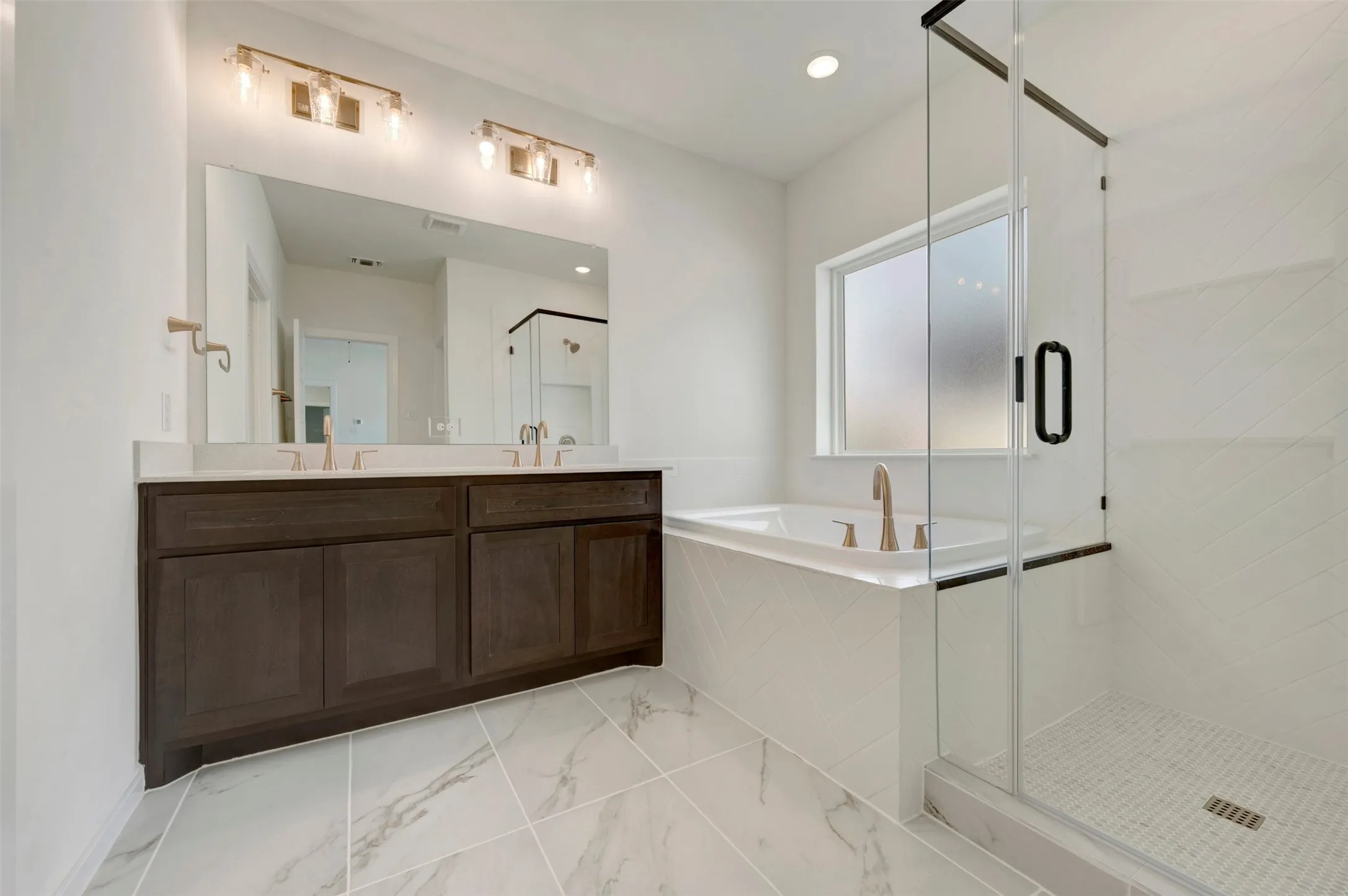 Dual vanity with a stone countertop, a built-in bathtub, a walk-in shower with glass enclosure, and large format floor tiling