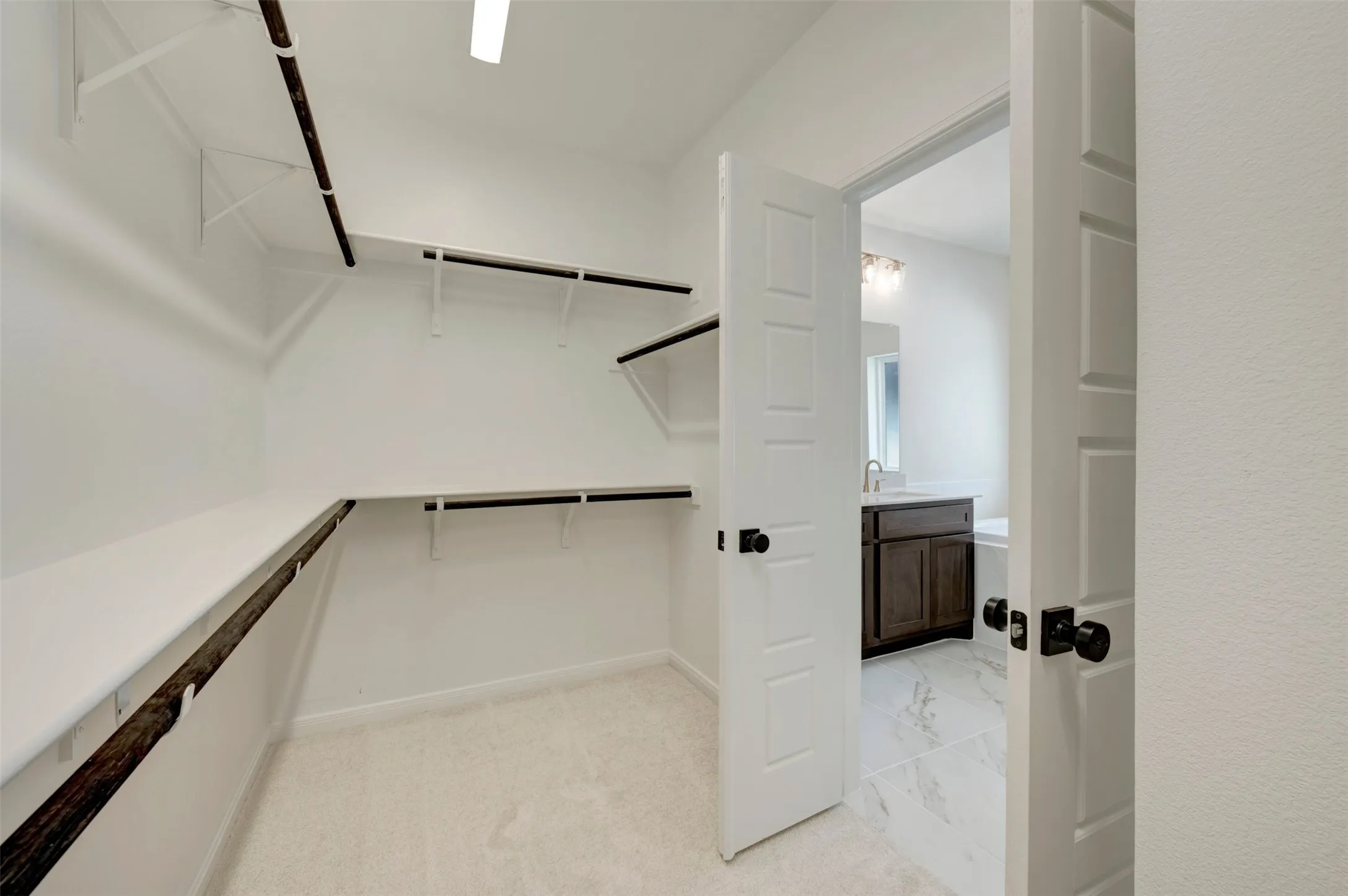 Walk-in closet with carpet flooring, white shelving, and hanging rods