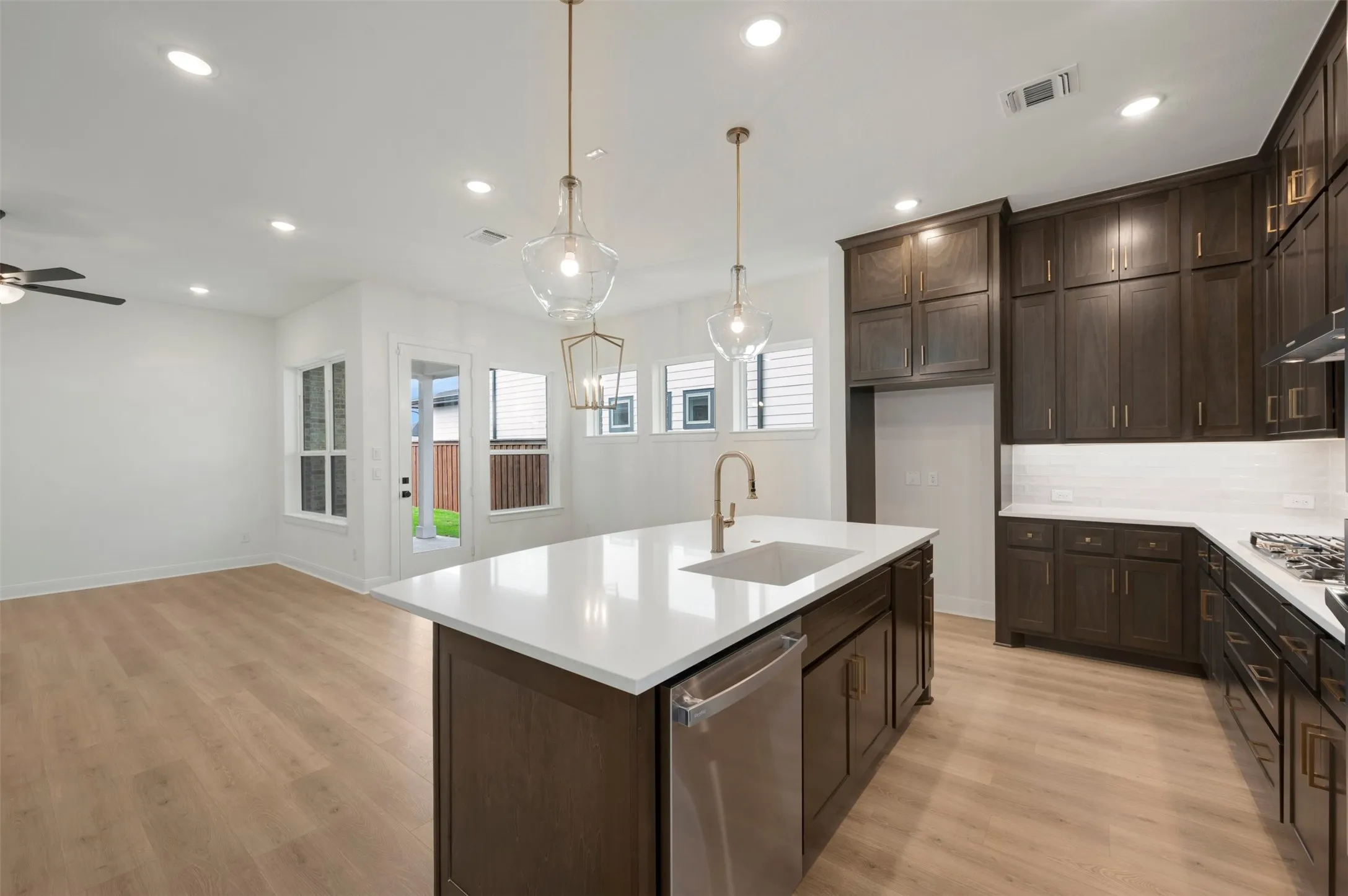 Kitchen featuring a large island with white countertop, dark wood-finish cabinetry, stainless steel dishwasher, and a gas range