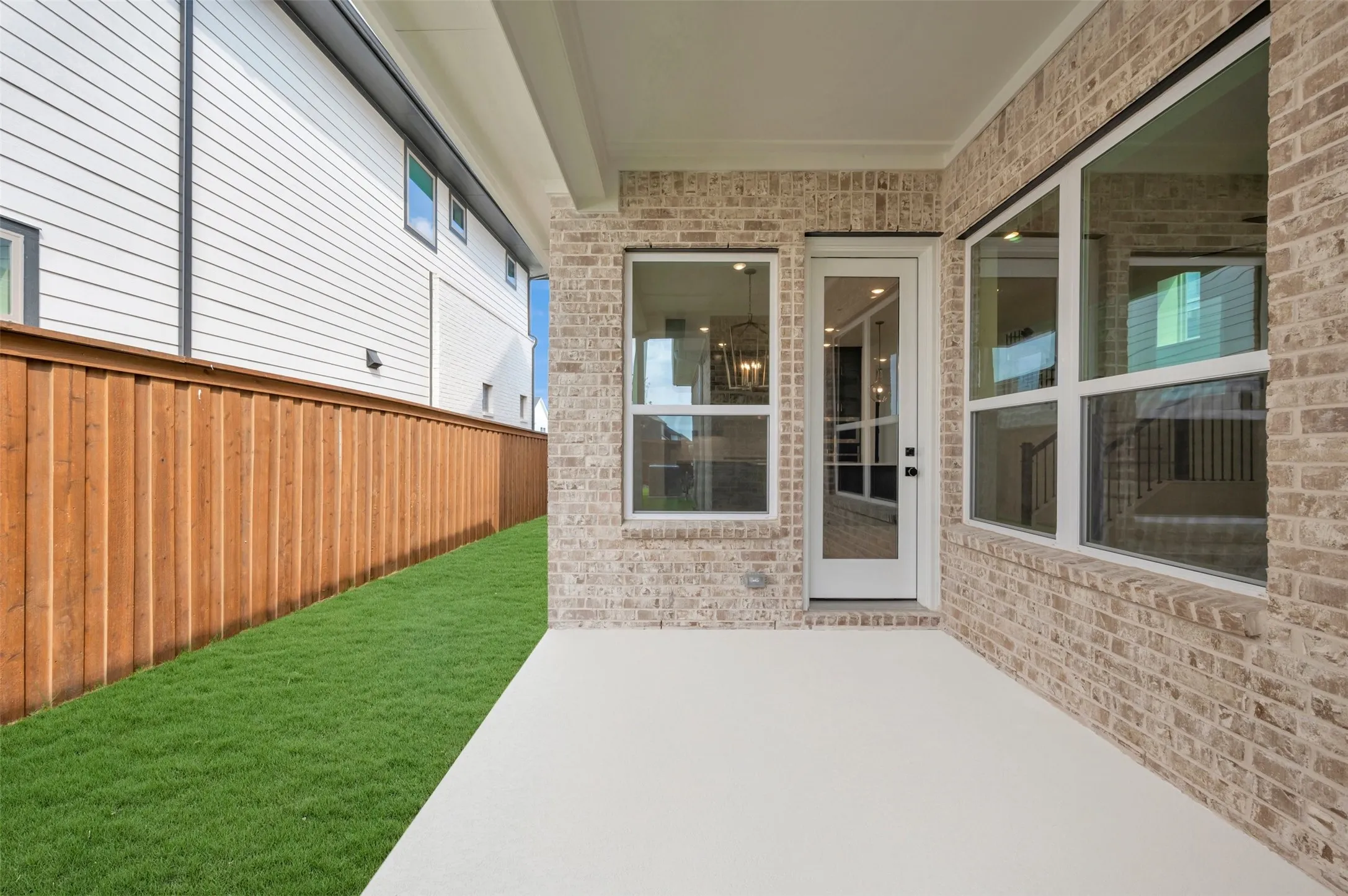 Covered patio featuring a concrete slab and light-toned brick exterior