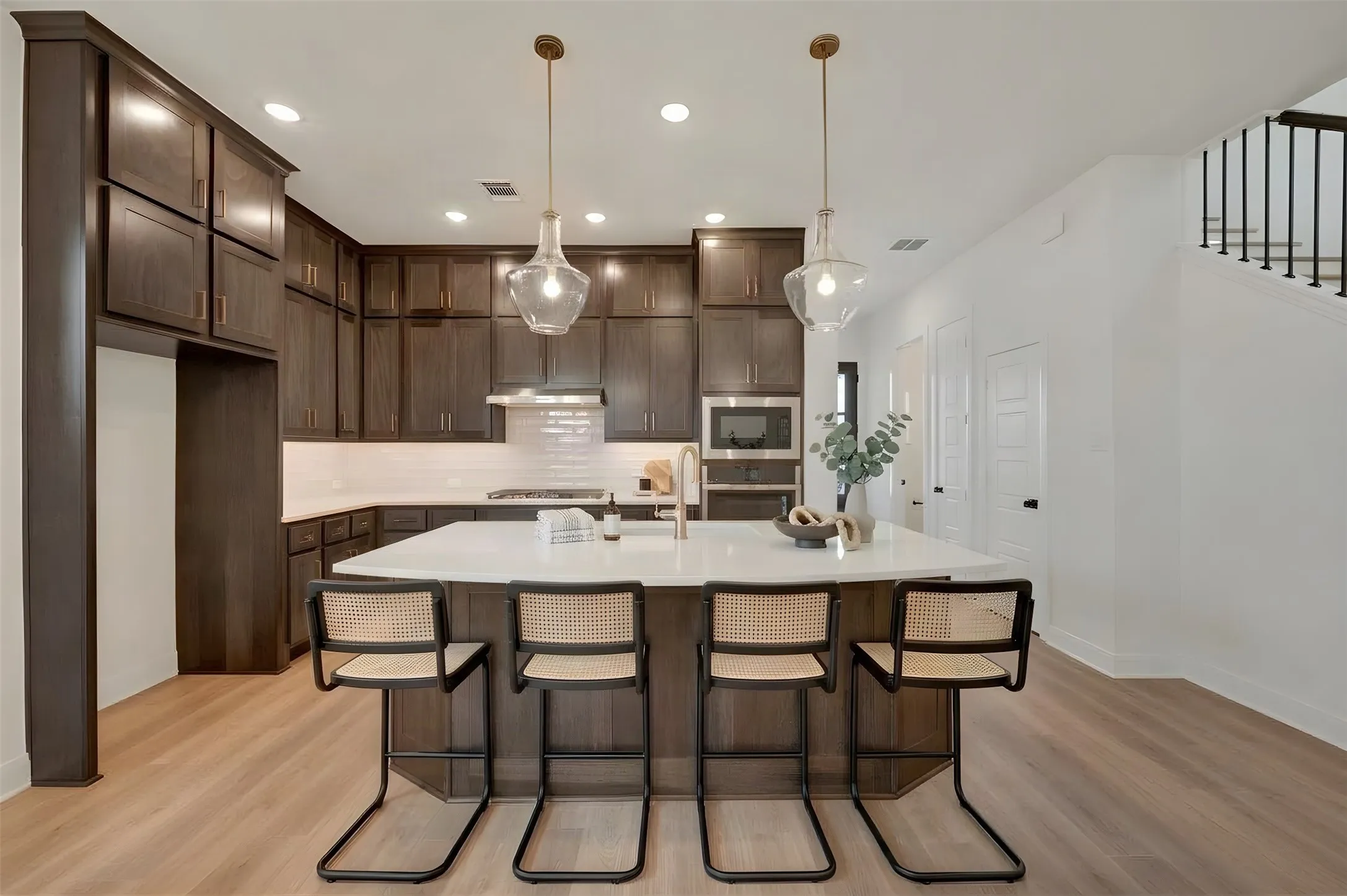 Kitchen featuring dark wood cabinetry, white subway tile backsplash, a large kitchen island with white countertop, and light wood-finish flooring