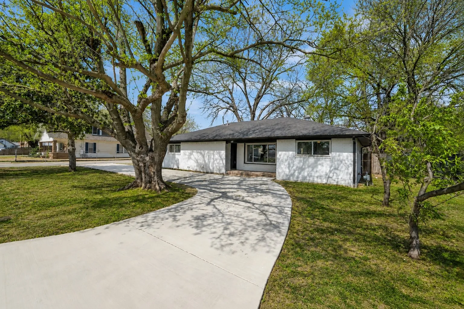 Charming exterior at 600 N Mill surrounded by mature trees and a spacious lawn.