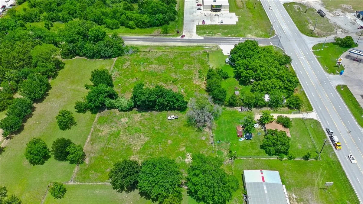 Expansive undeveloped land parcel featuring mature trees, a cleared area, and direct road frontage